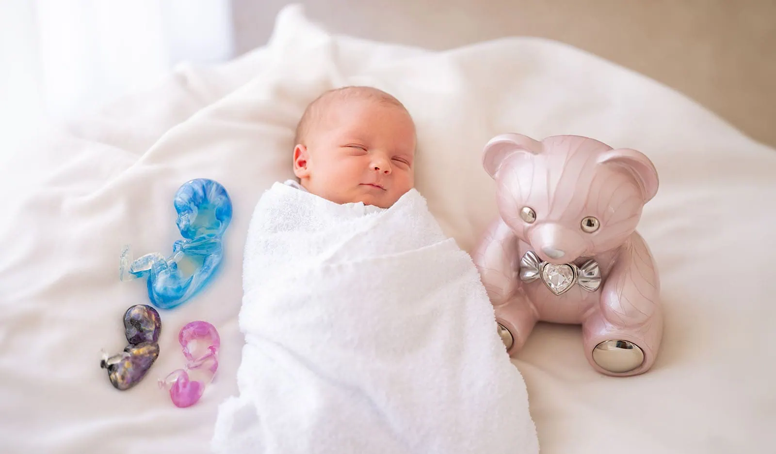 baby spencer's newborn shoot 71 Peaceful newborn baby sleeping next to colorful keepsakes and a pink teddy bear.