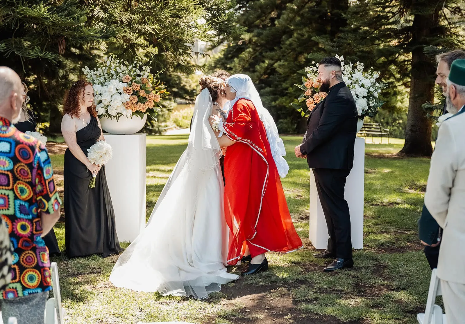 botanic gardens, araucaria avenue wedding - jade & hazim 31 Newlyweds sharing first kiss at outdoor wedding with lush greenery and floral decor.
