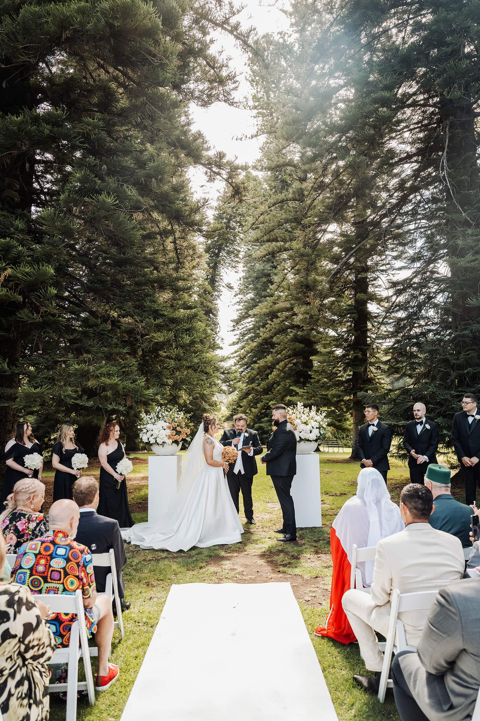 botanic gardens, araucaria avenue wedding - jade & hazim 40 Outdoor wedding ceremony in a serene coniferous forest setting.