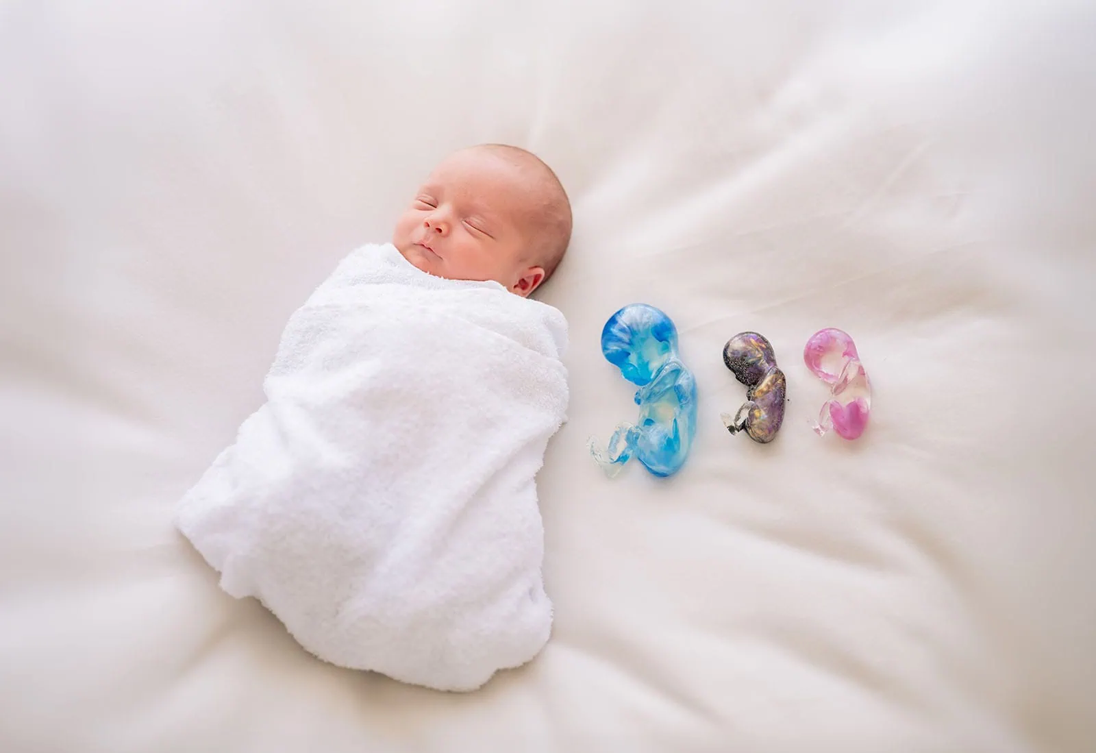 baby spencer's newborn shoot 69 Newborn baby sleeping peacefully next to colorful candy-like decorations.