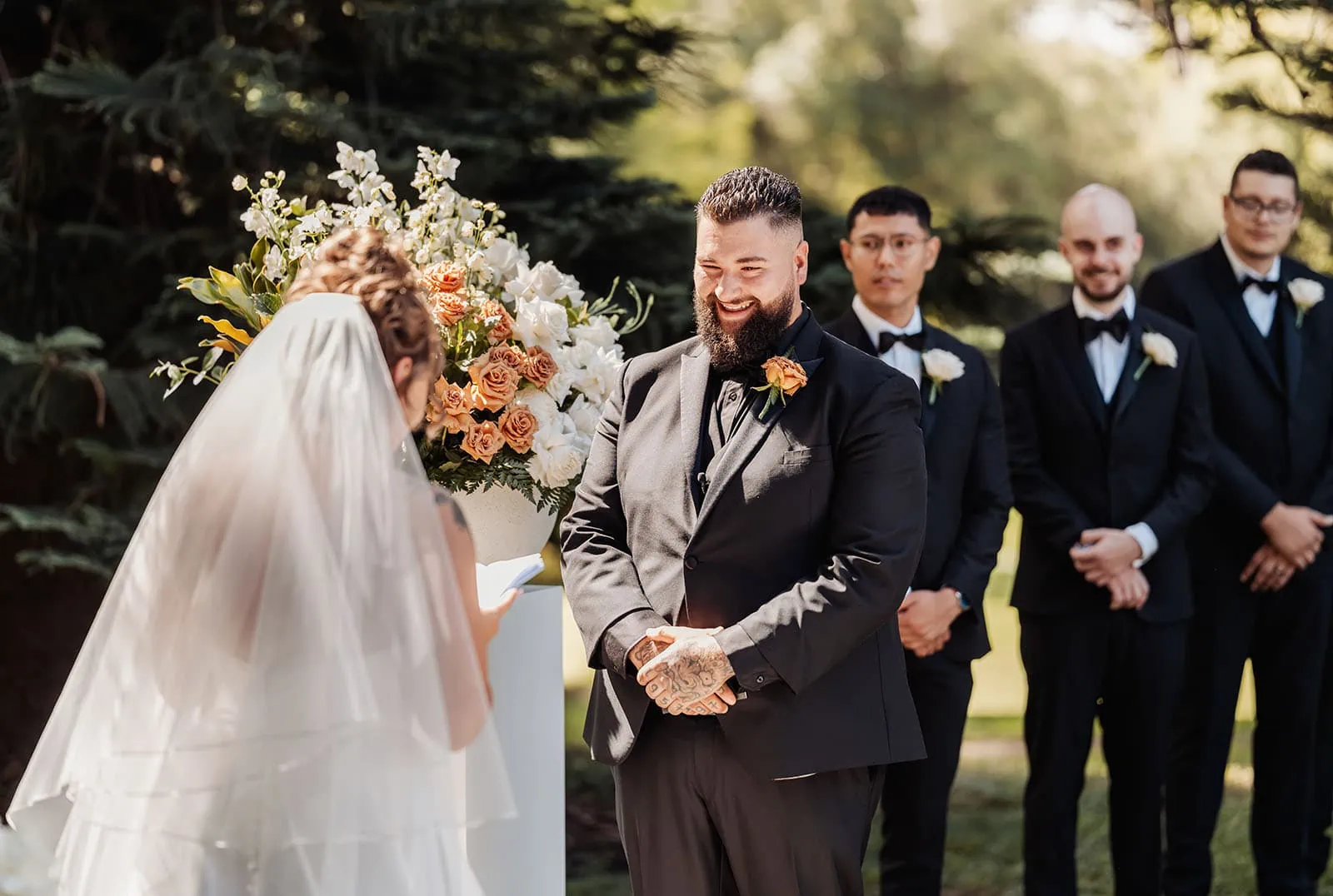 botanic gardens, araucaria avenue wedding - jade & hazim 35 Bride and groom exchanging vows in sunlit outdoor wedding ceremony.