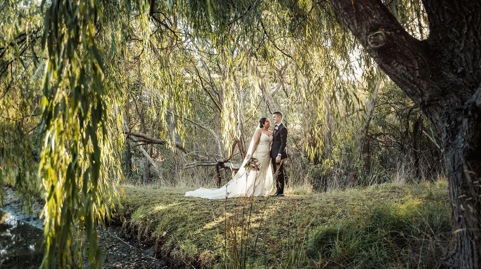the lane vineyard 5 Bride and groom share a tender moment under willow trees by a pond.