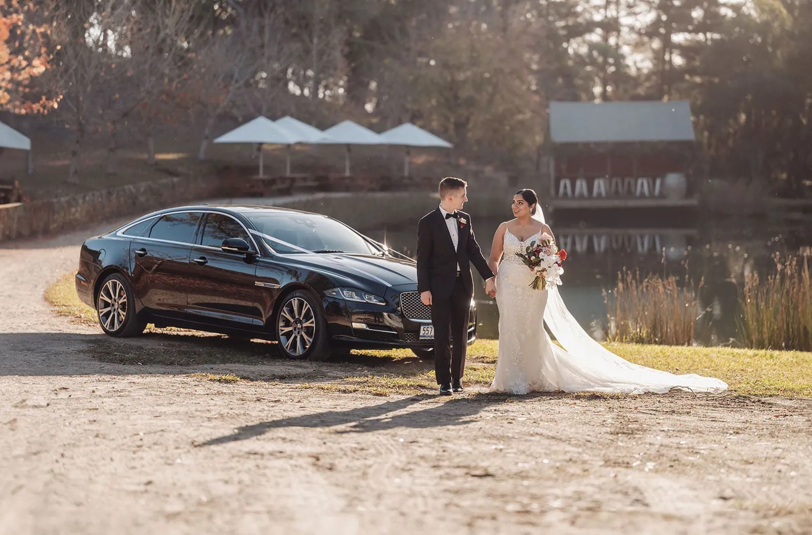 the lane vineyard 8 Newlywed couple by luxury car near serene lakeside at sunset.