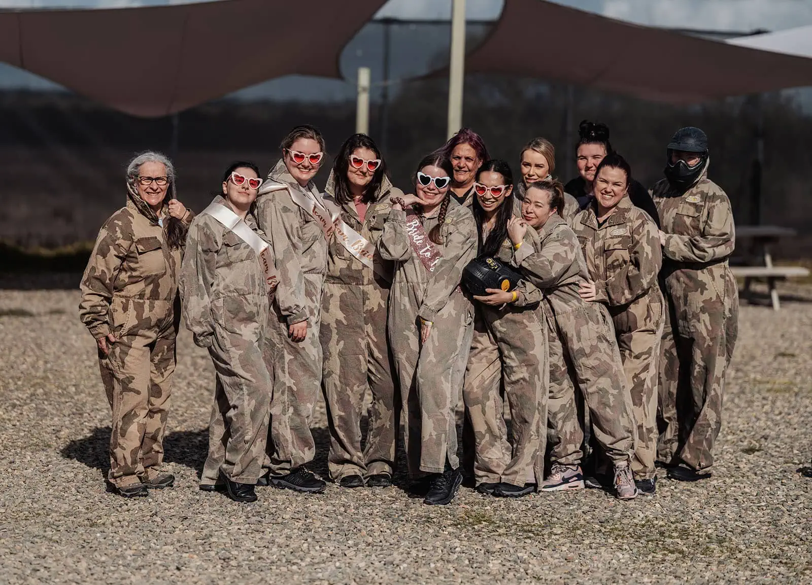 monarto delta force bucks vs hens paintball party 4 Group of friends in camouflage jumpsuits celebrating bachelorette party outdoors.