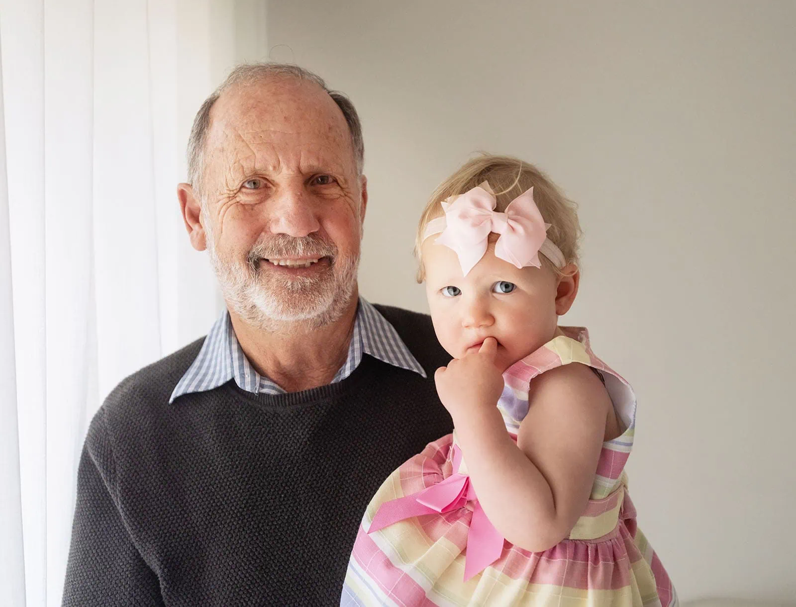 baby joshua's newborn photo shoot 41 Elderly man holding toddler granddaughter, both smiling warmly.
