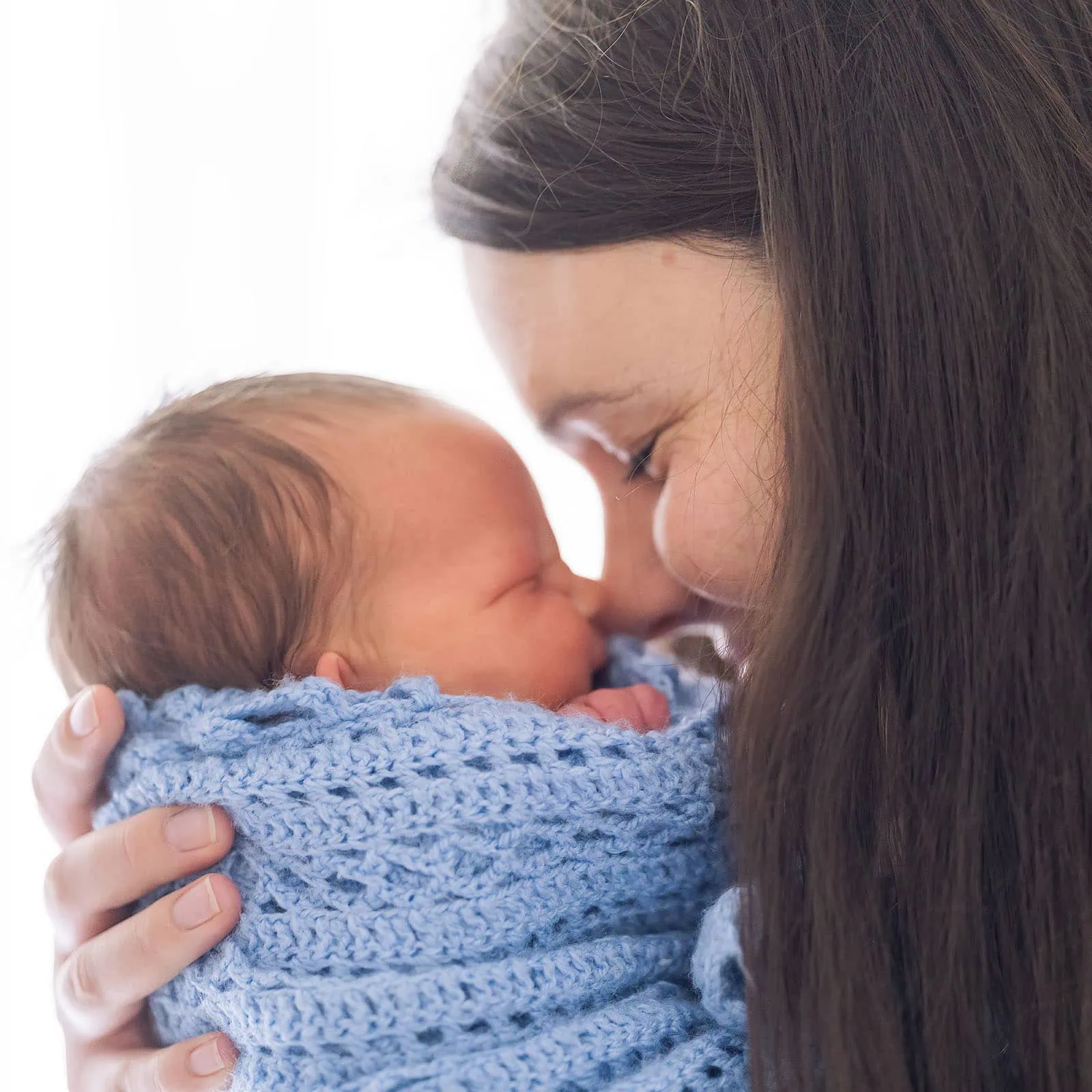 baby joshua's newborn photo shoot 35 Mother lovingly holds newborn baby close, showcasing tender bond and pure affection.