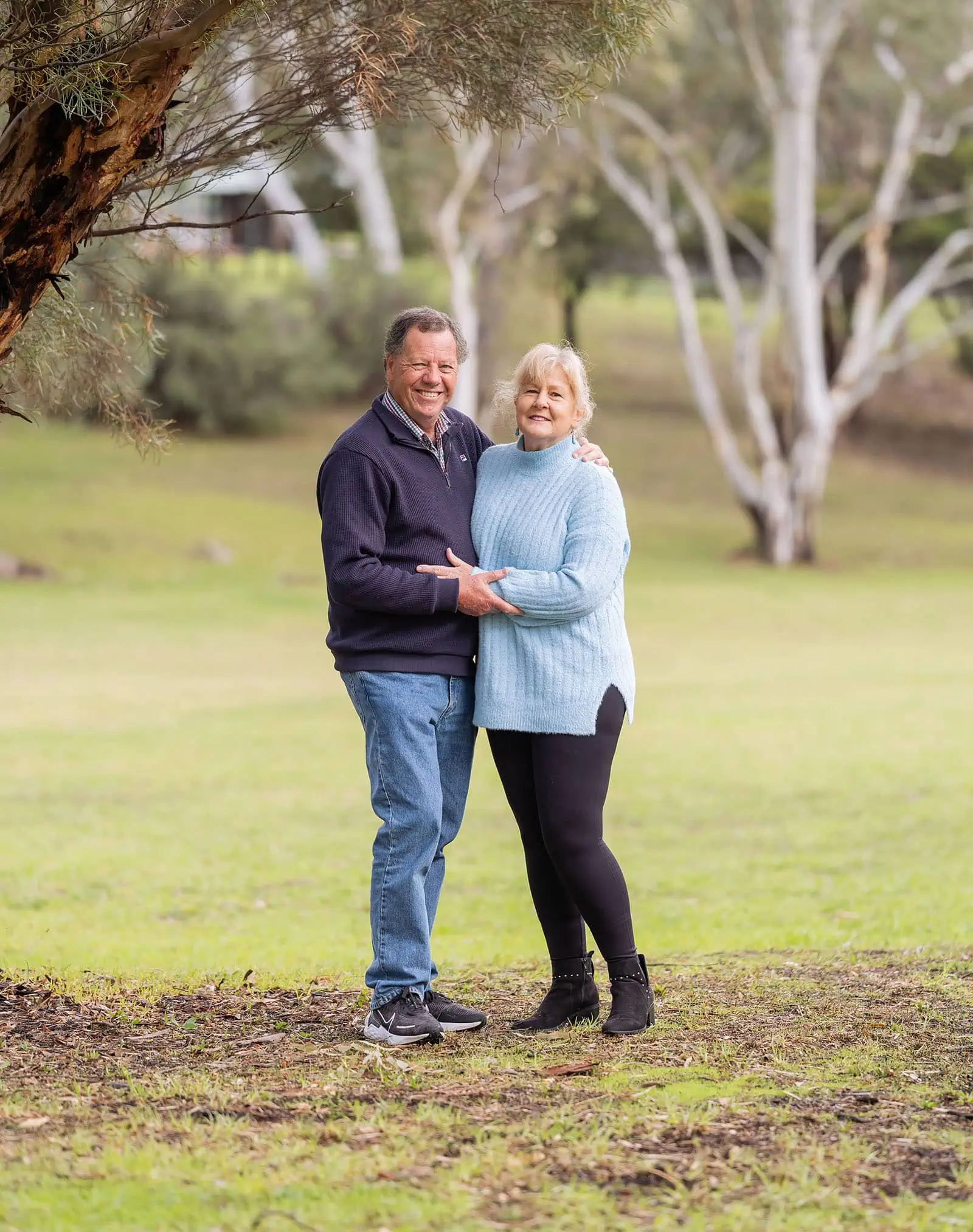 baby joshua's newborn photo shoot 33 Older couple embracing in a tranquil eucalyptus park.