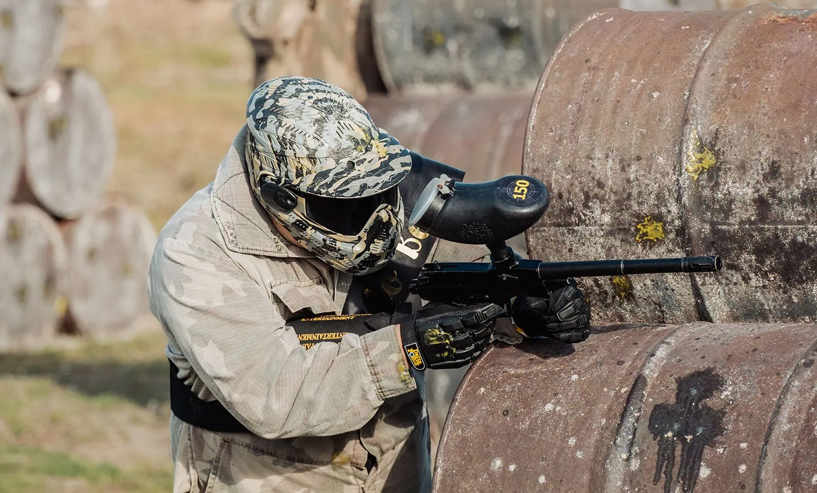 monarto delta force bucks vs hens paintball party 26 Paintball player in camouflage gear aiming behind cover.