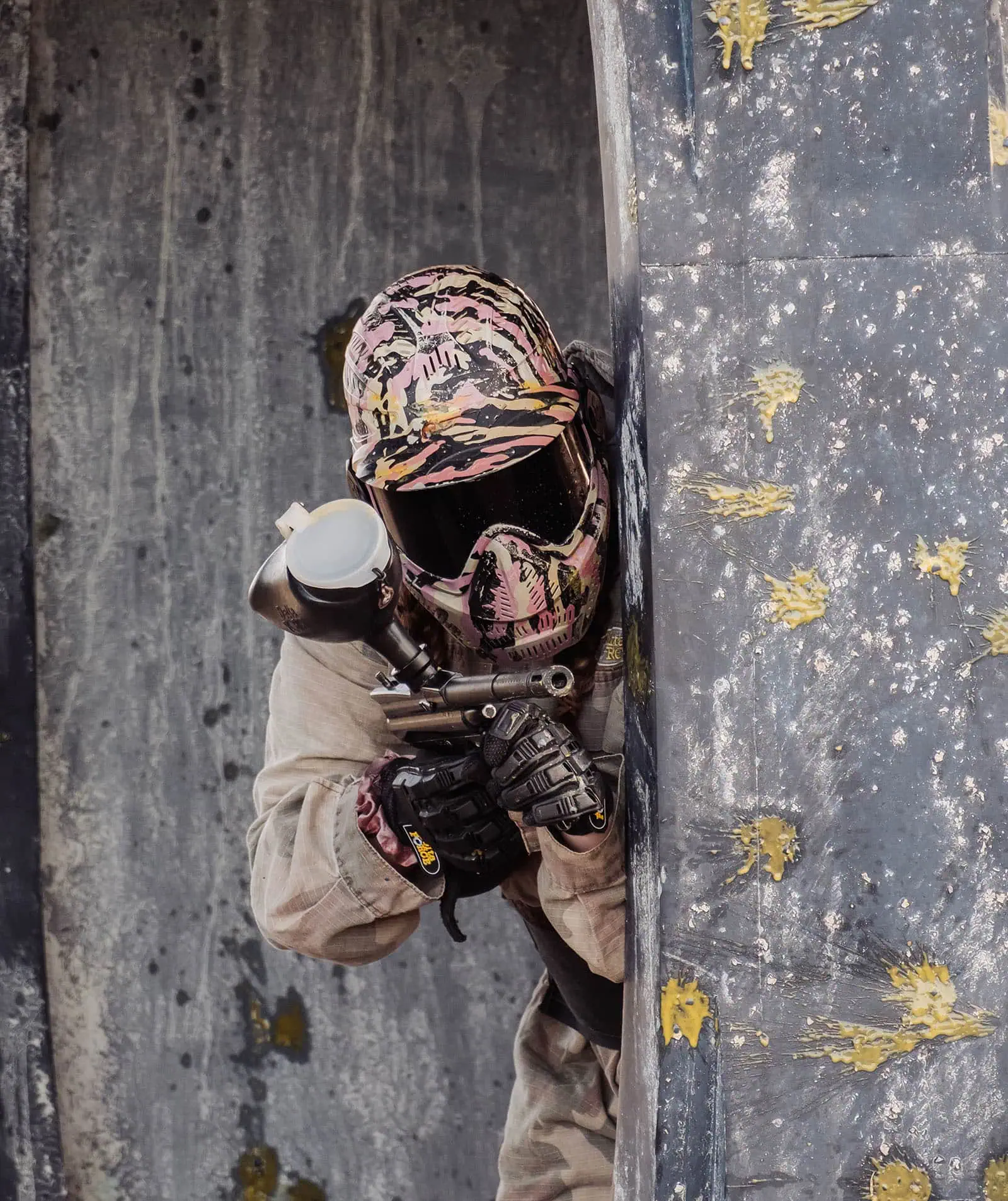 monarto delta force bucks vs hens paintball party 35 Paintball player in action, hiding behind barrier with paint splatters, ready to shoot.