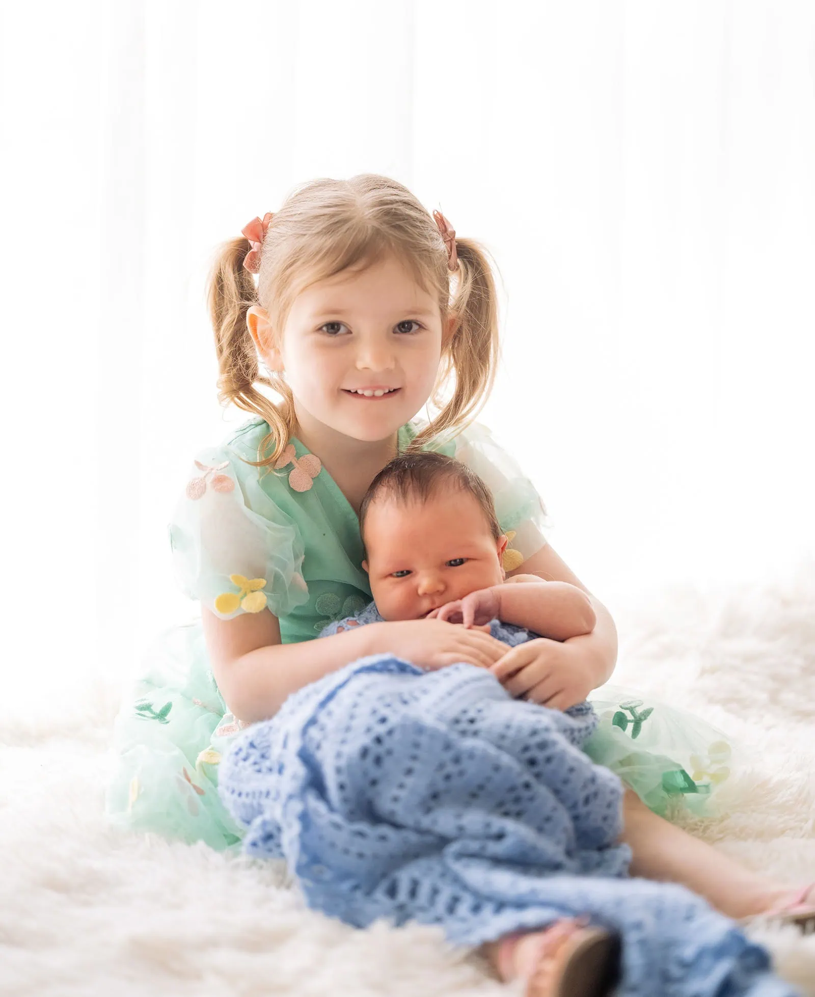 baby joshua's newborn photo shoot 39 Young girl holding baby sibling in cozy, heartwarming moment.