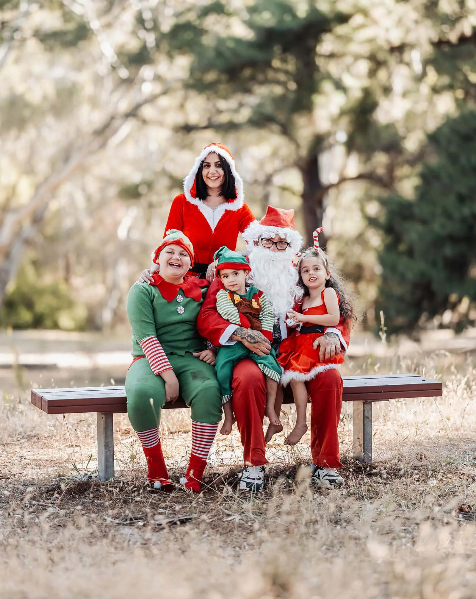 last minute father christmas photoshoot 40 Festive family portrait with Santa, Mrs. Claus, elves in outdoor Christmas setting.