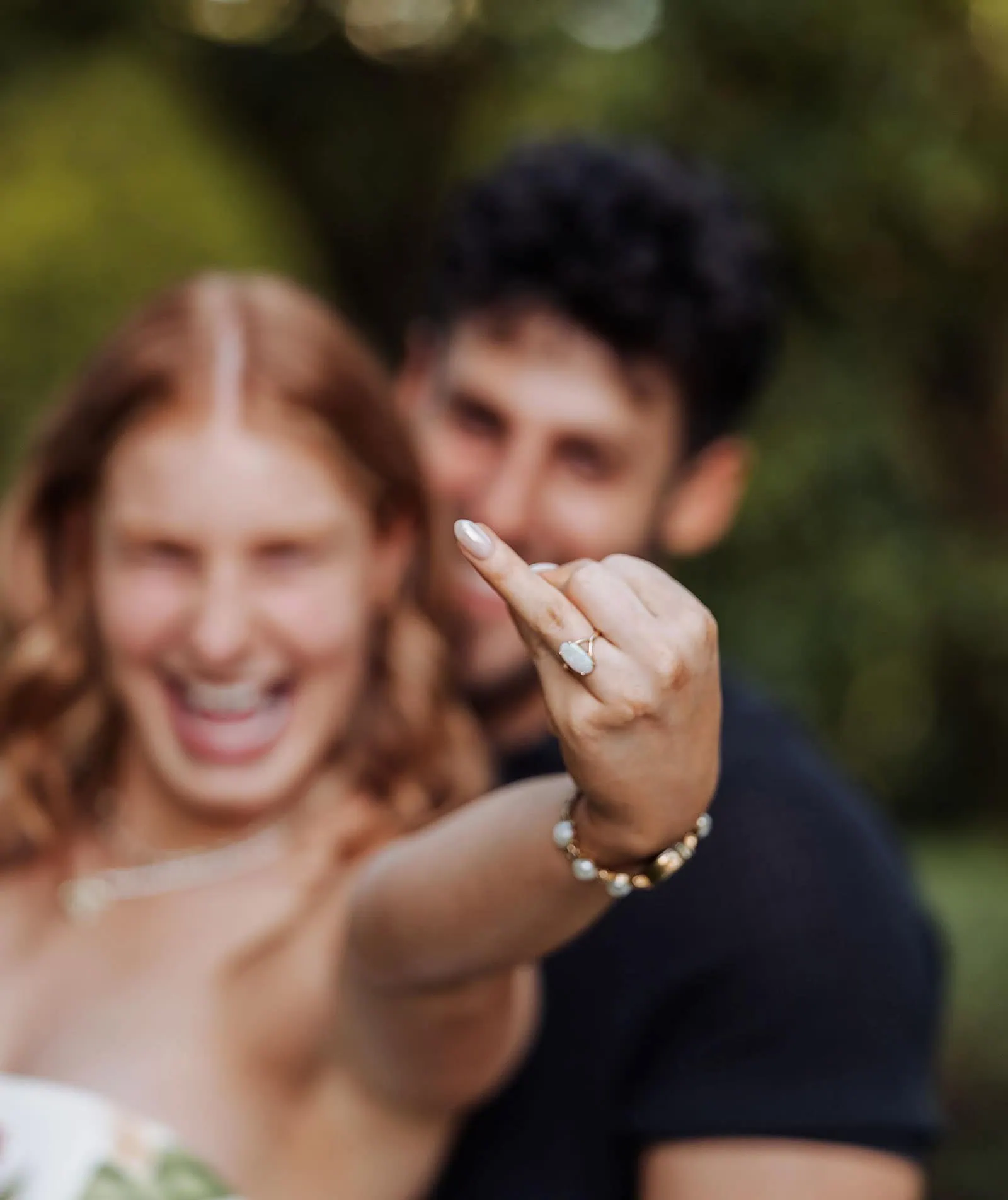 engagement rings under $2,000: 7 designs that don't look cheap 8 Woman showcasing engagement ring with partner in joyful outdoor celebration.