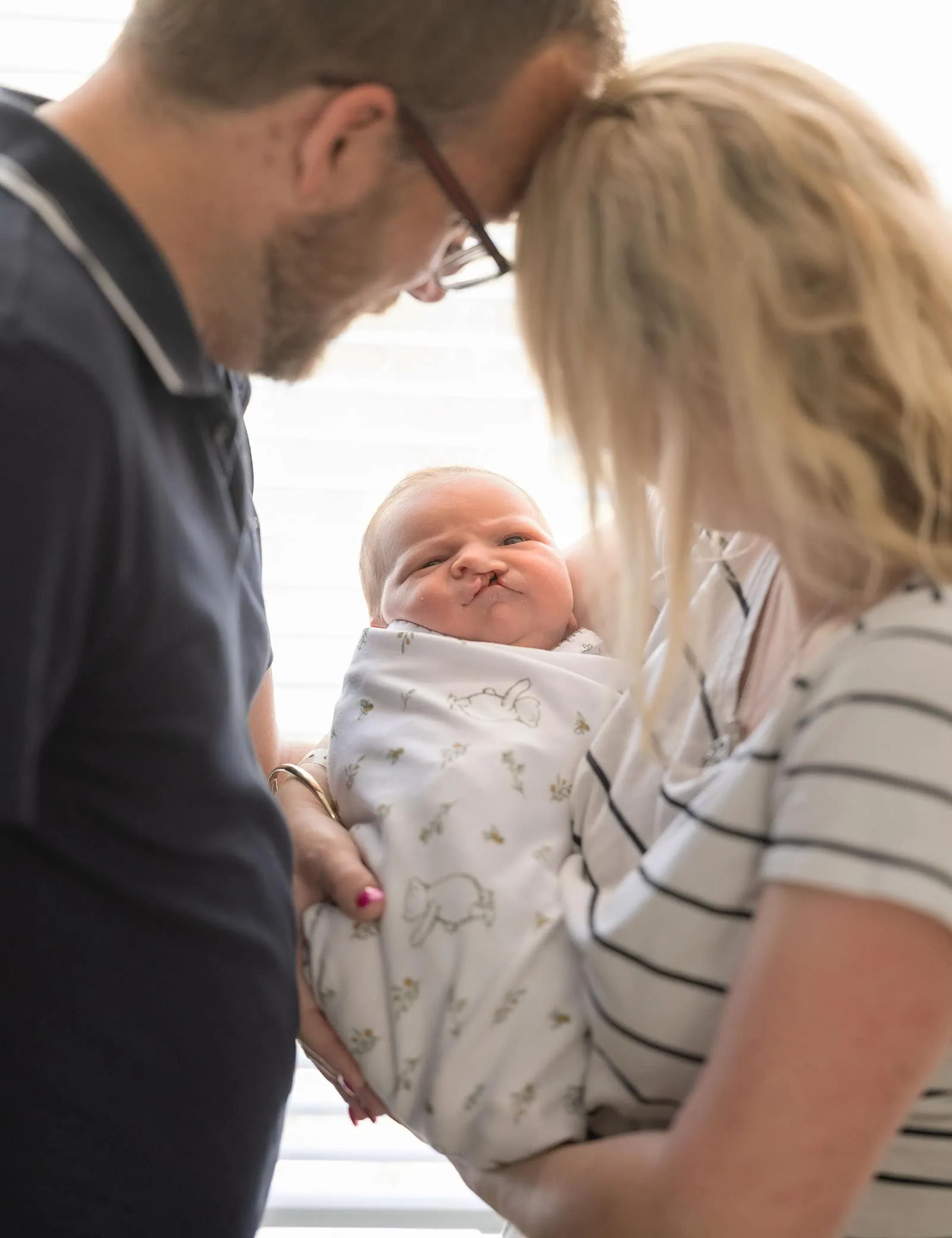 baby walker - flinders medical center newborn photography 5 Loving couple cradles newborn, bathed in warm light, symbolizing family unity and tenderness.