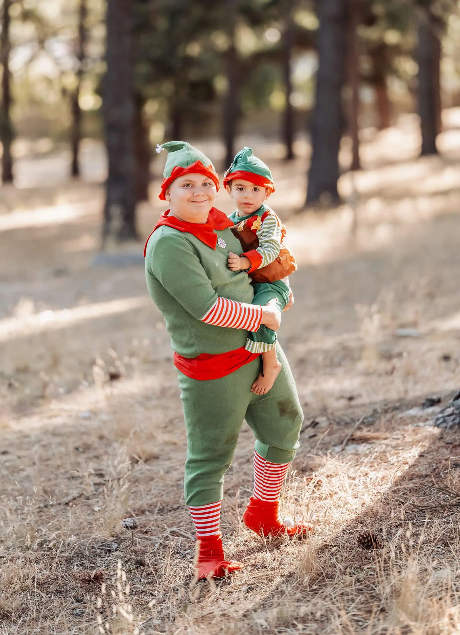 last minute father christmas photoshoot 41 Festive elf-clad duo in tranquil, sunlit forest, celebrating holiday joy and connection.