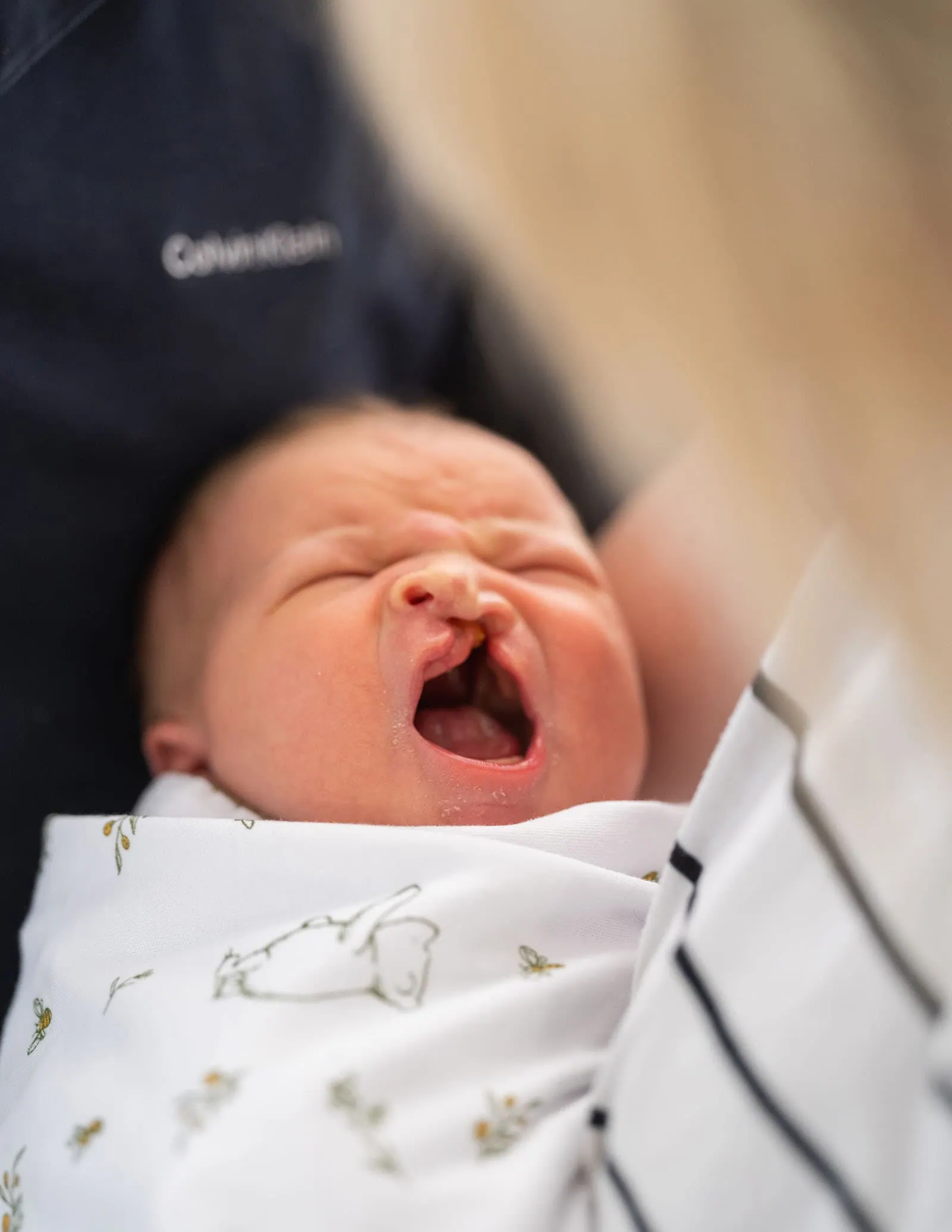 baby walker - flinders medical center newborn photography 4 Newborn baby wrapped in animal-patterned blanket, yawning; soft lighting and parental presence.