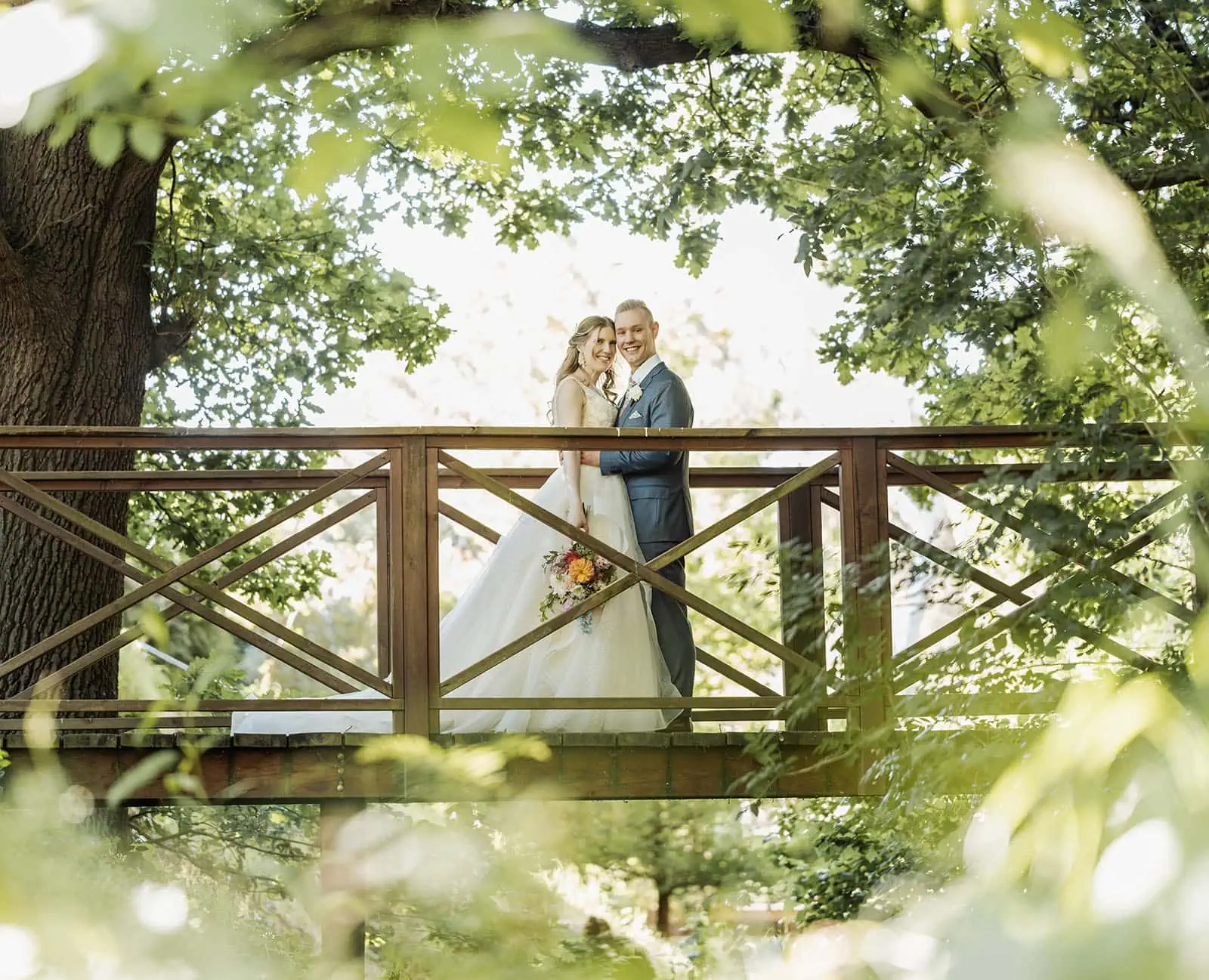 inglewood inn 11 Romantic newlywed couple on rustic bridge surrounded by lush green summer foliage.