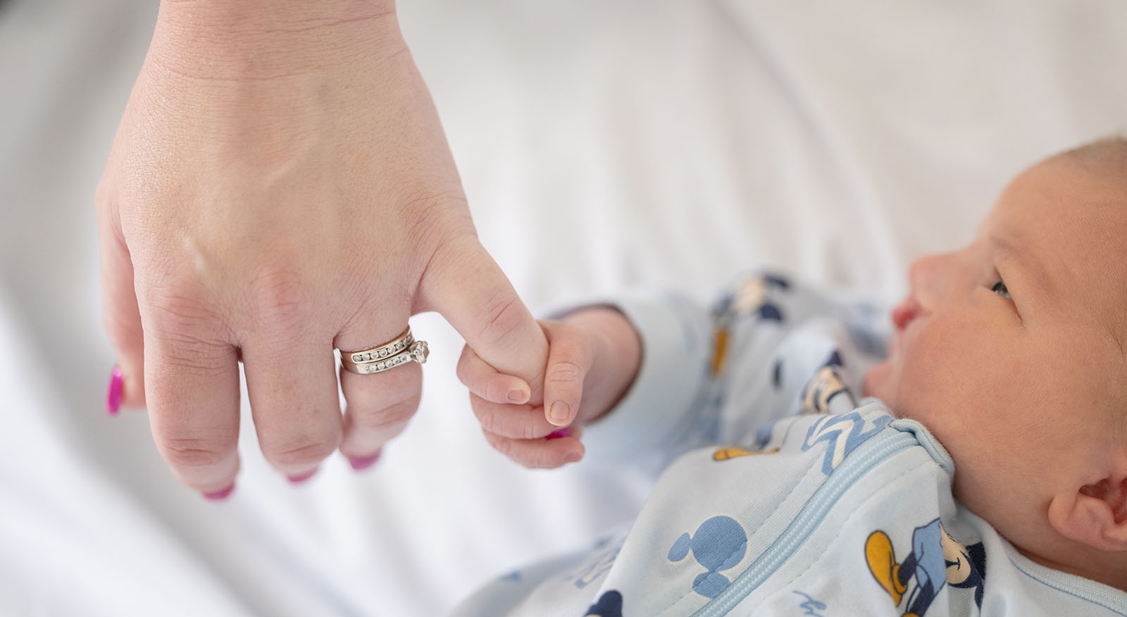 baby walker - flinders medical center newborn photography 11 Newborn hand grasps parents finger, symbolizing love, care, and early bonding moments.