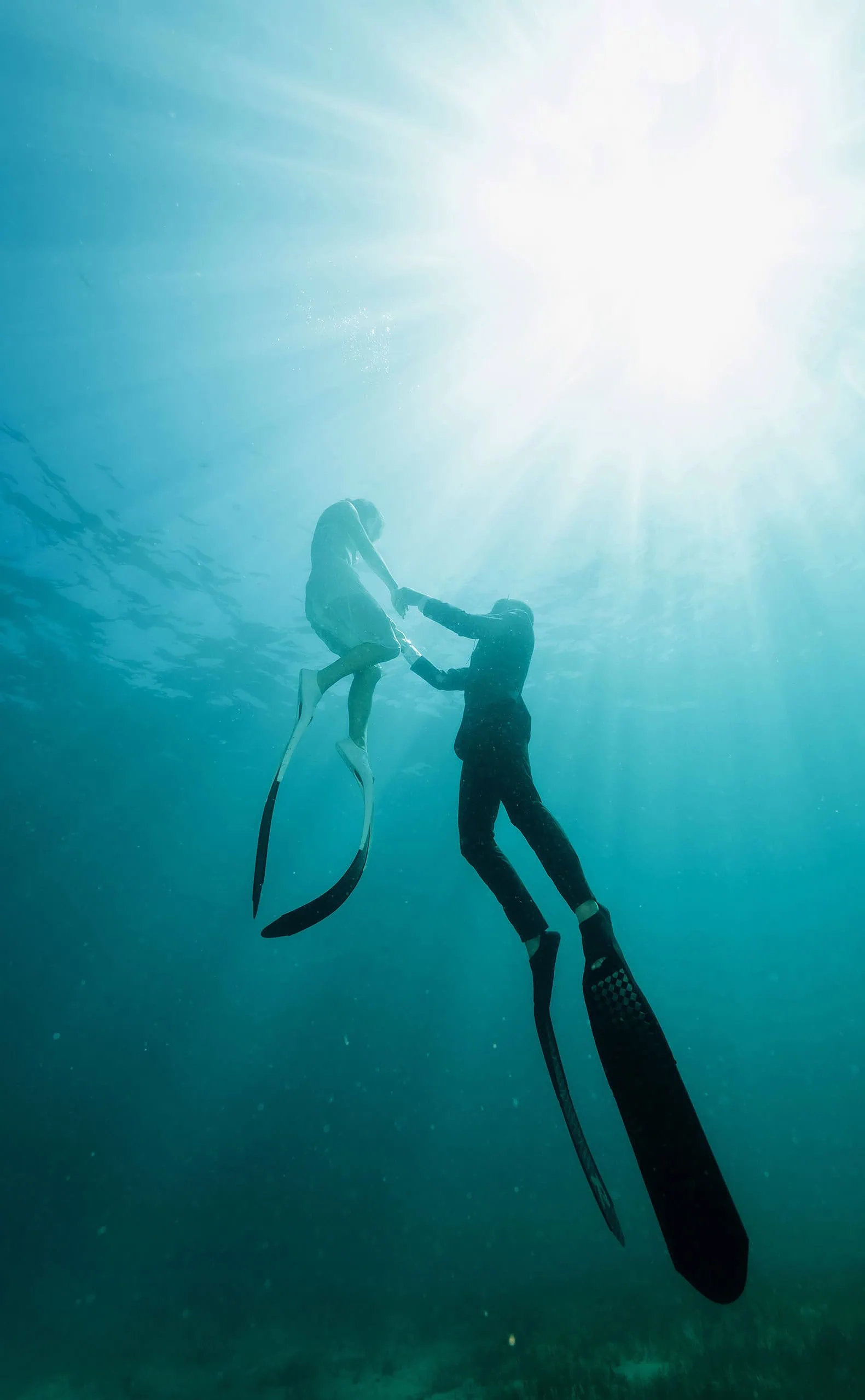pt noarlunga underwater wreck the dress shoot - jess & jack 13 Divers in elegant attire gracefully moving in a sunlit, serene underwater setting.