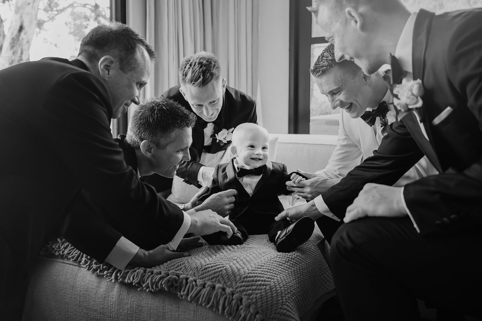 50 creative ways to use qr codes at your wedding | happlee 4 Infant in tuxedo surrounded by smiling men at formal event, black and white photo.