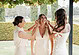 Bride with bridesmaids in cream dresses, outdoor wedding scene, joyful atmosphere.