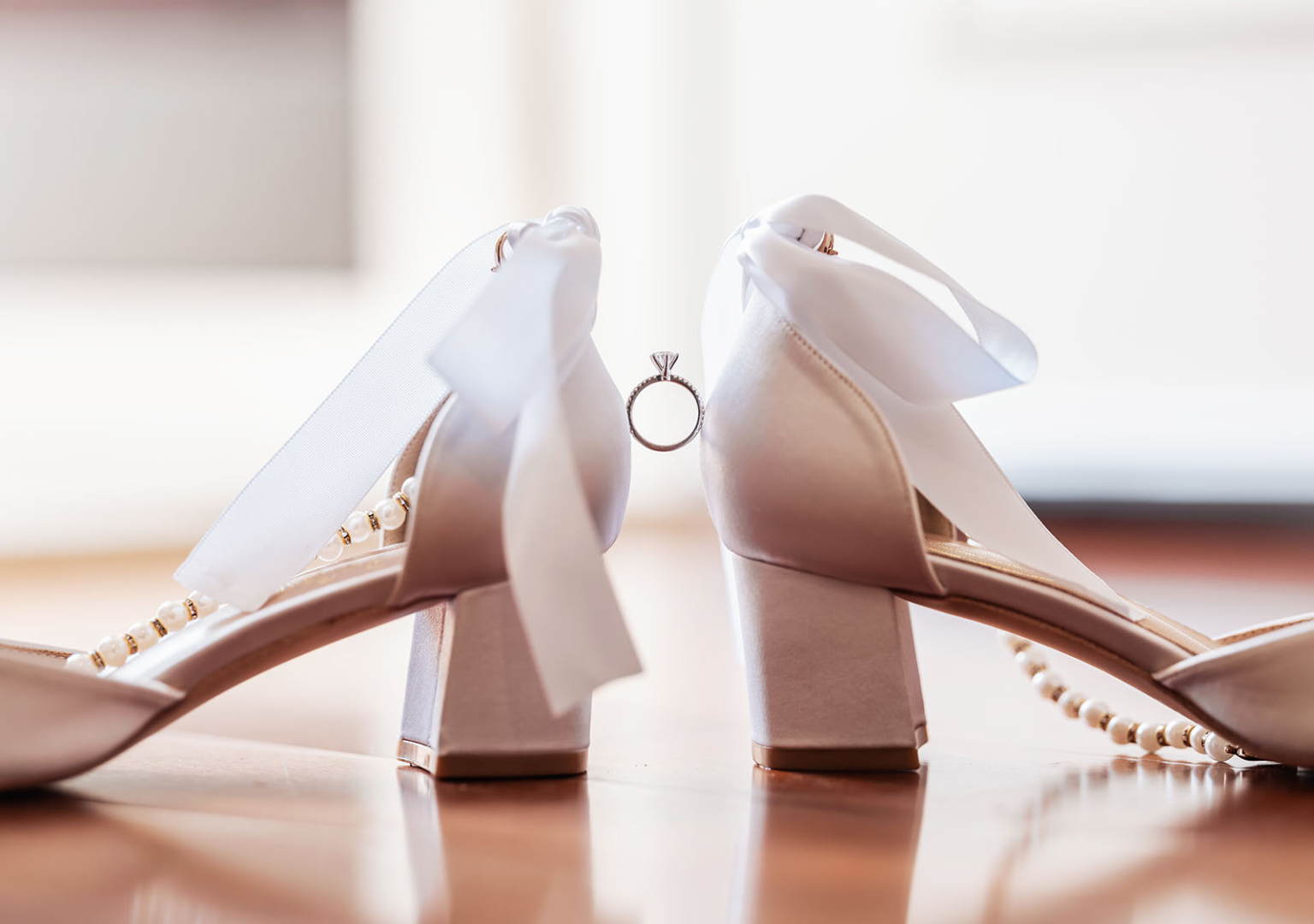 crystal meanings in bridal rings: spiritual symbolism behind the stones 25 Elegant block-heeled satin shoes with a diamond engagement ring on polished wooden floor.
