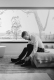 Man in formal attire tying shoes, preparing for event, natural light, elegant simplicity.