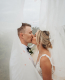 Bride and groom share a romantic kiss under ethereal fabric on their wedding day.