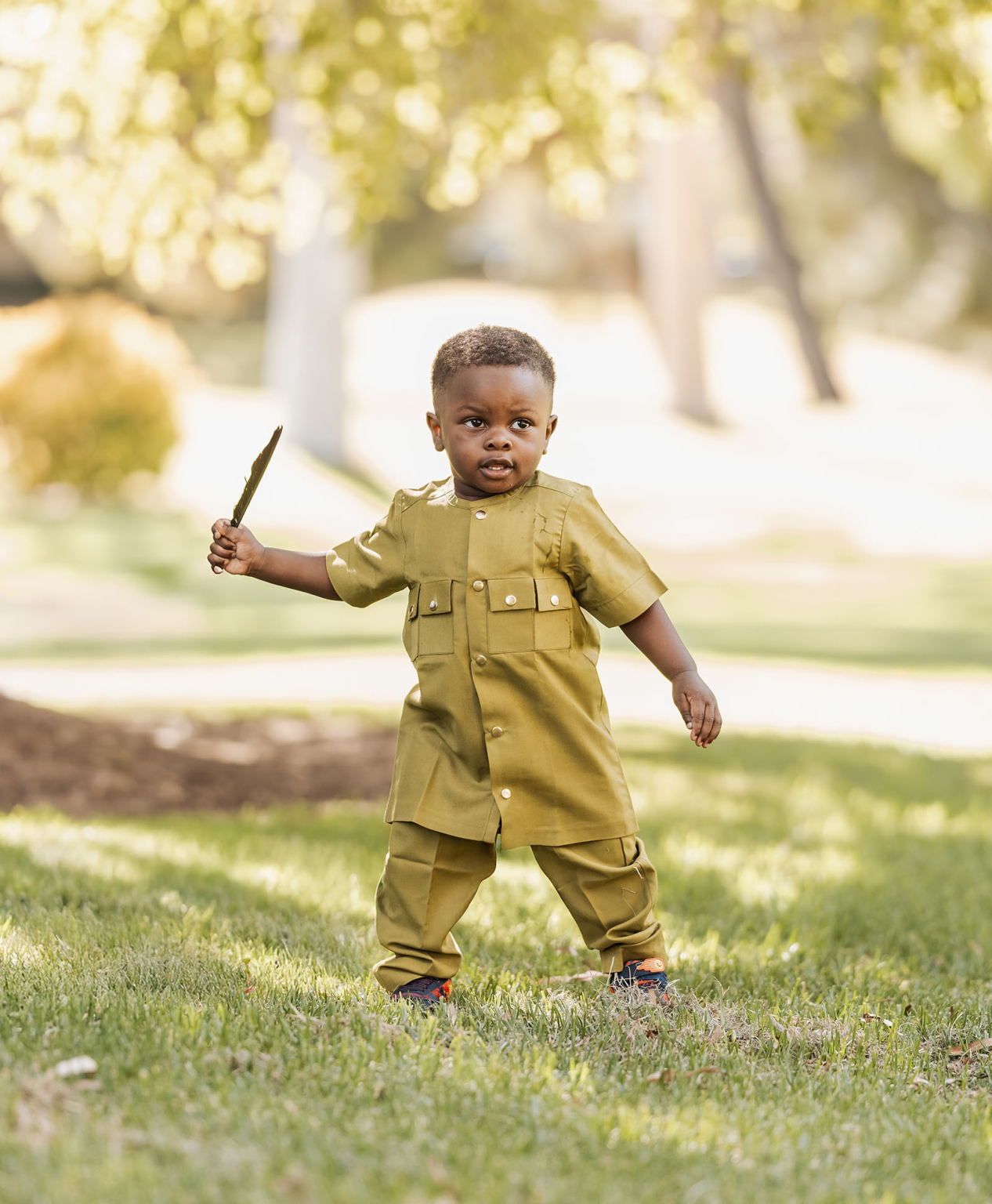 family photoshoot in veale gardens 20 Child playing outdoors in uniform on sunlit lawn, exploring nature with joy.