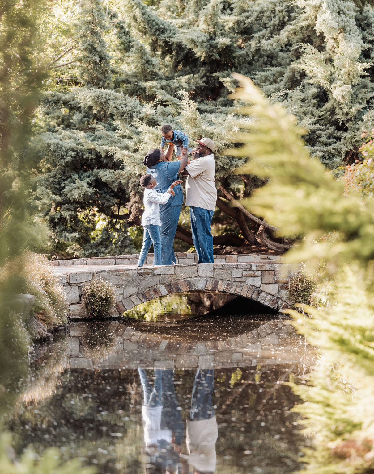 family photoshoot in veale gardens 5 Family bonding on a stone bridge in nature, surrounded by lush greenery.