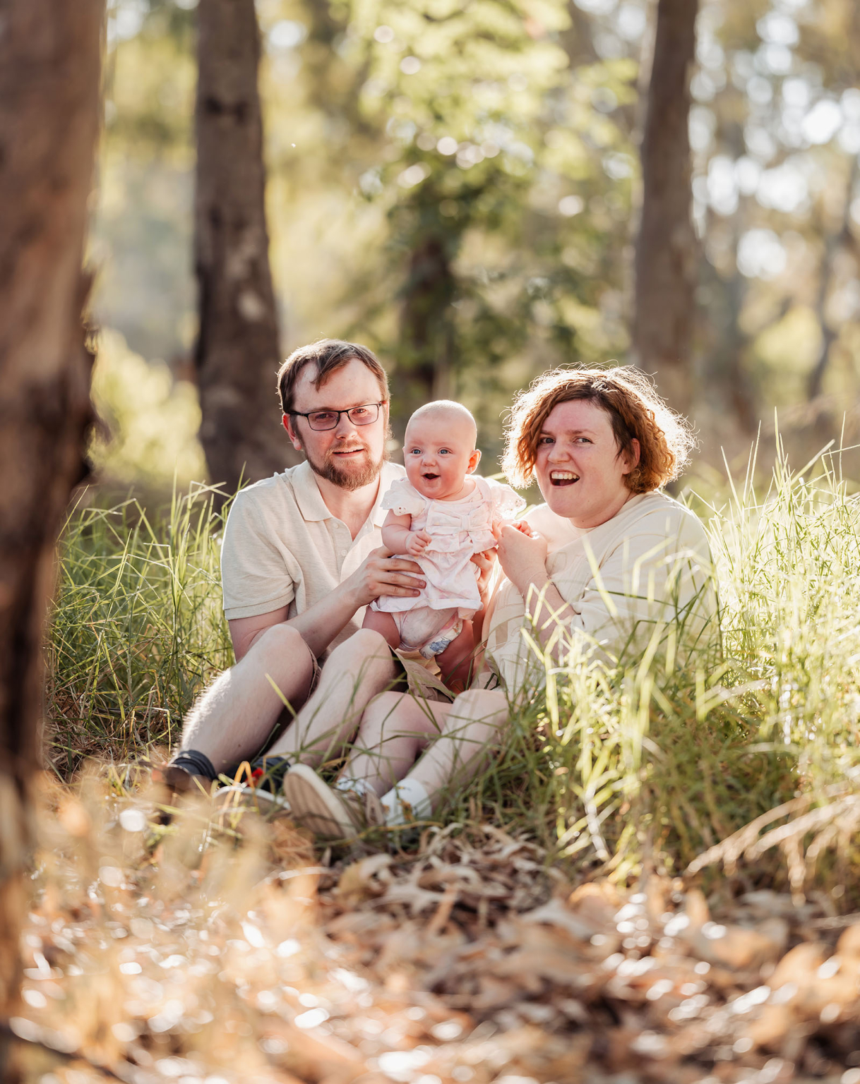 carisbrooke park family photoshoot 77 Family enjoying a peaceful, sunlit moment in a forest setting.