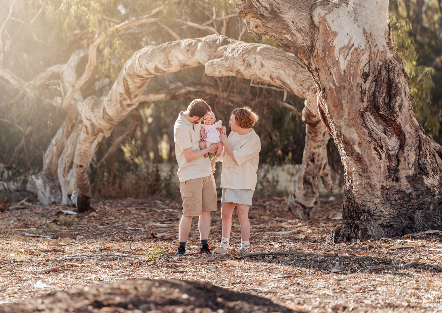 carisbrooke park family photoshoot 70 Family bonding in serene wooded setting, surrounded by trees and gentle sunlight filtering through.