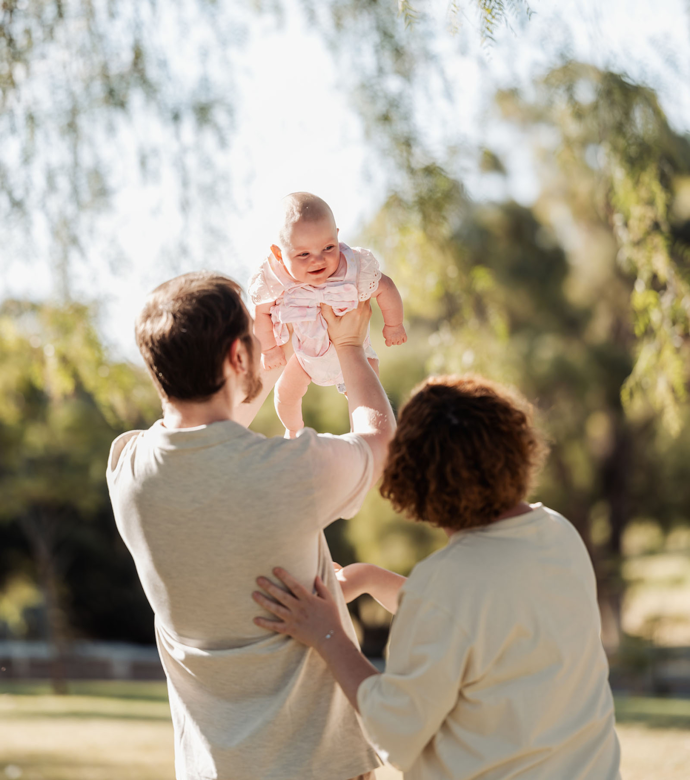 carisbrooke park family photoshoot 62 Joyful family moment with a baby in a sunlit park.