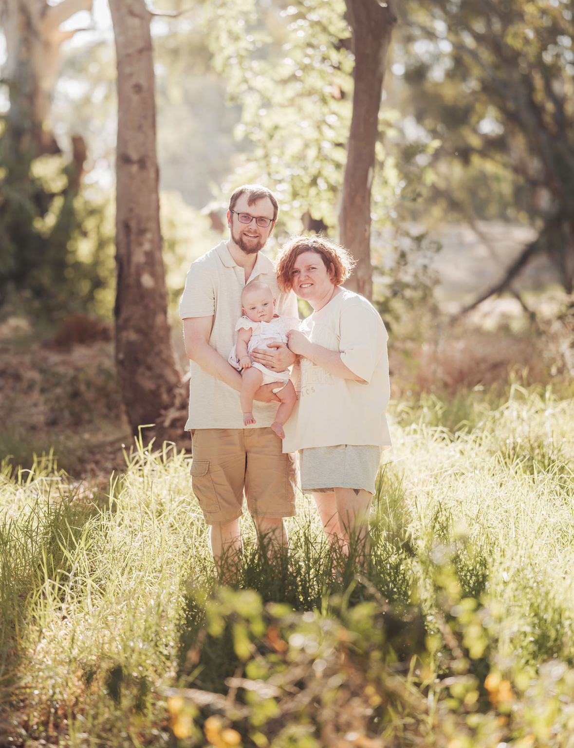 carisbrooke park family photoshoot 76 Family enjoying the outdoors with baby in peaceful, sunlit forest setting.