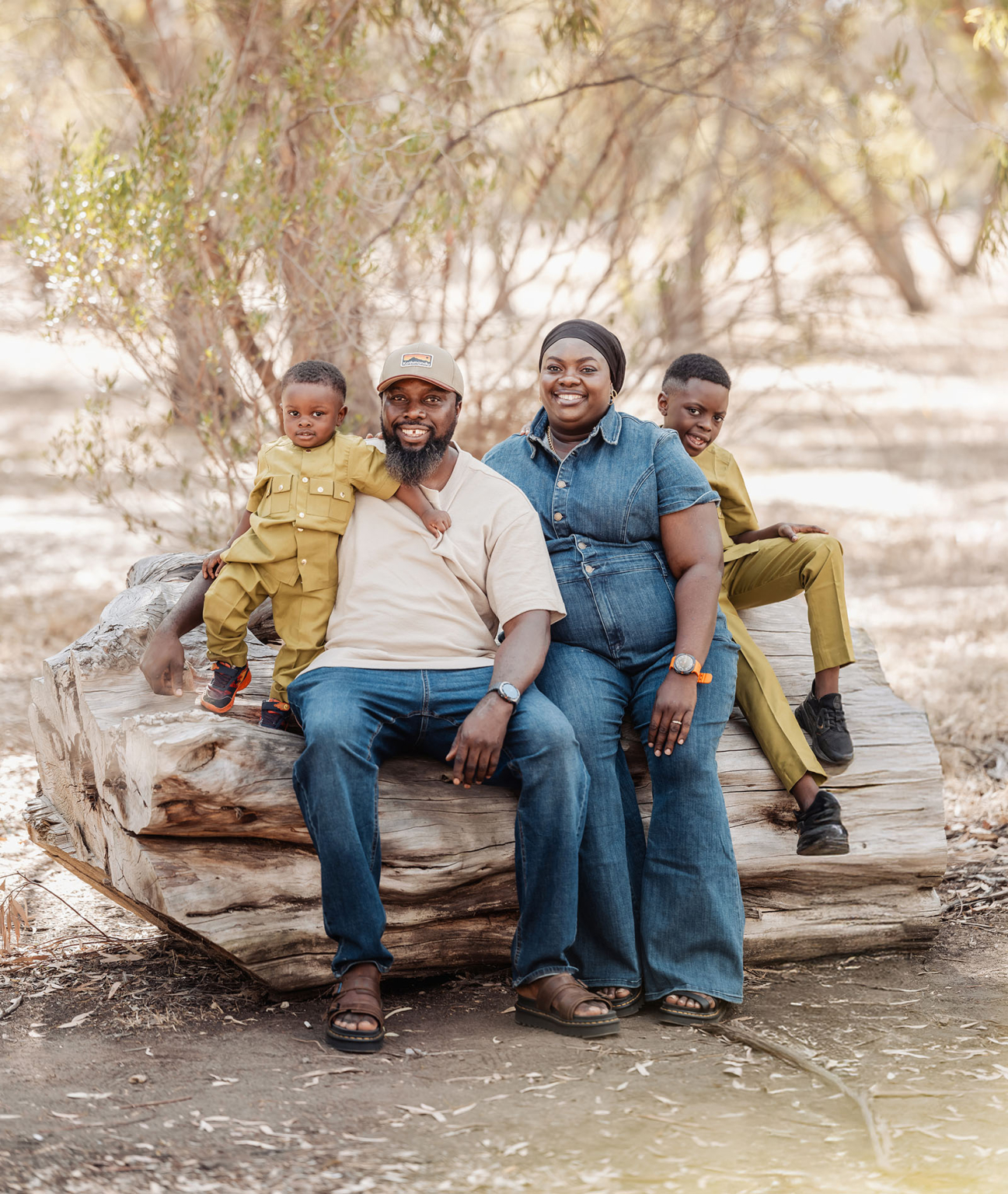 family photoshoot in veale gardens 24 Family enjoying a sunny day in woodland, sitting on a tree trunk together.