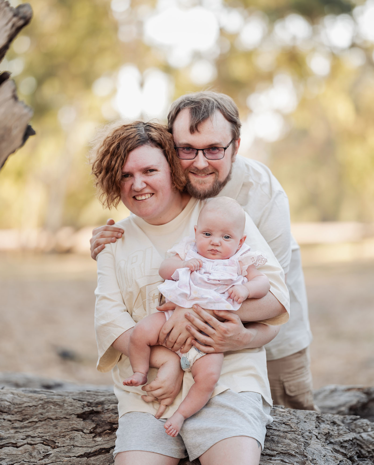 carisbrooke park family photoshoot 72 Happy family with baby outdoors, enjoying nature and bonding under golden sunlight.