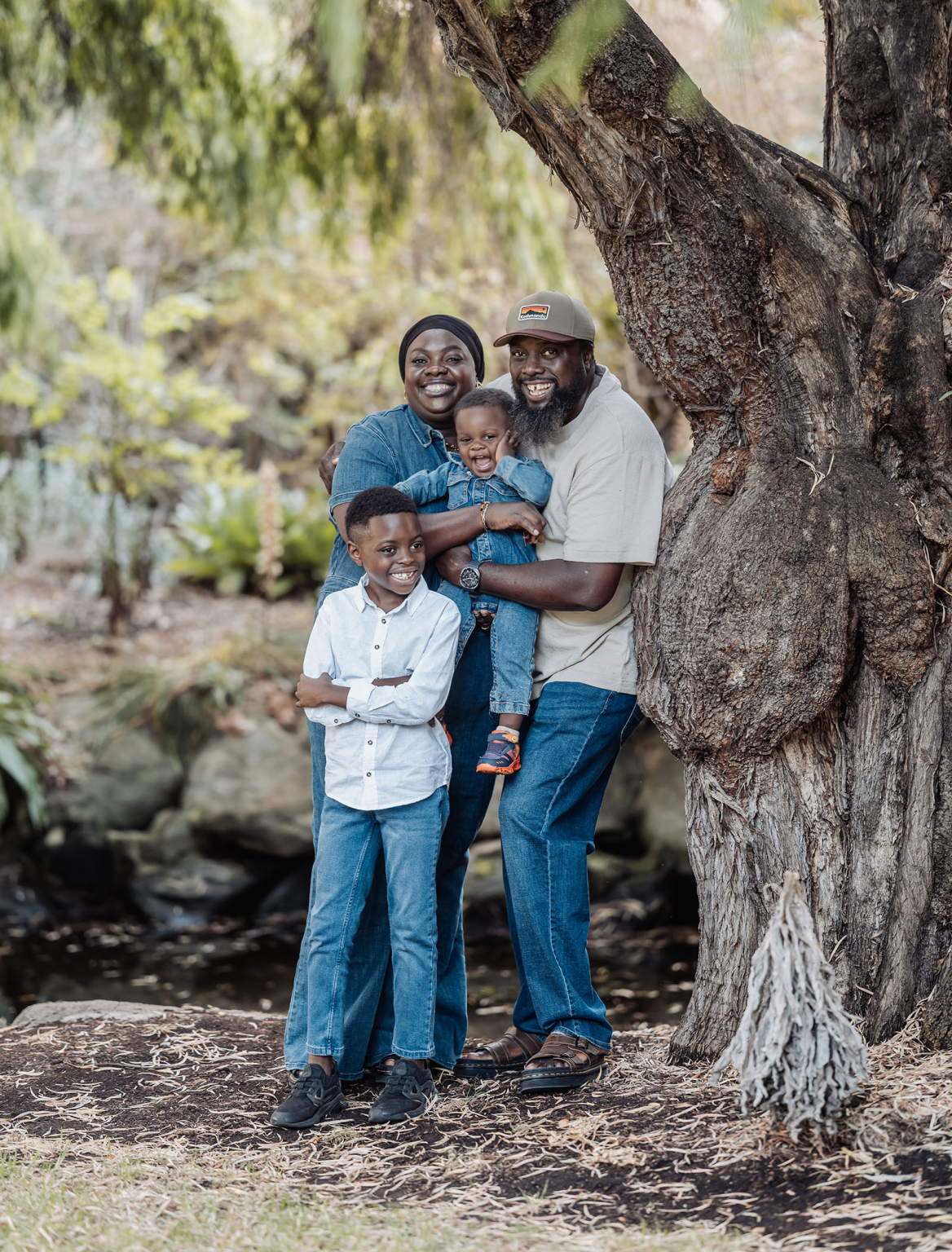family photoshoot in veale gardens 10 Happy family of four outdoors by tree, expressing joy and unity in natural setting.