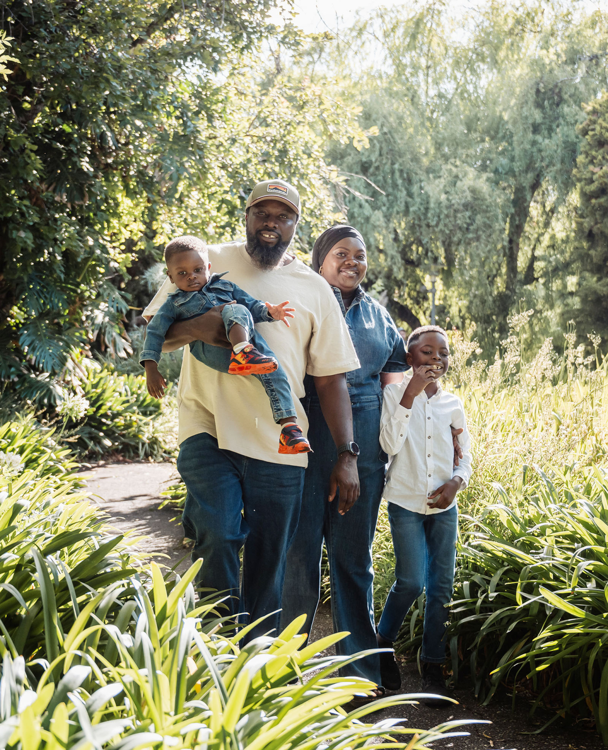 family photoshoot in veale gardens 9 Family enjoying a sunny day in a lush garden, exuding joy and togetherness.