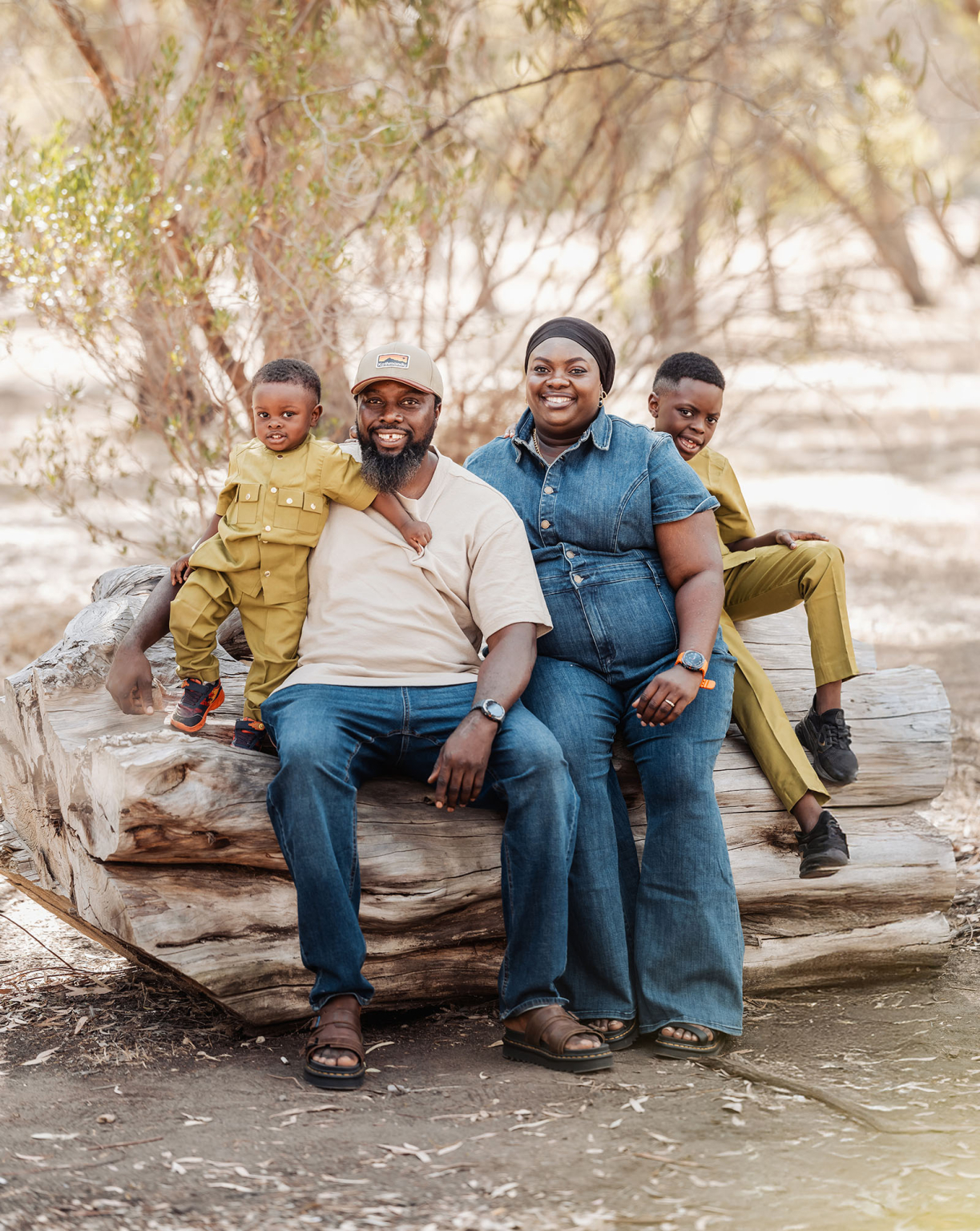 family photoshoot in veale gardens 23 Family enjoying a sunny day on a log in a forest setting.