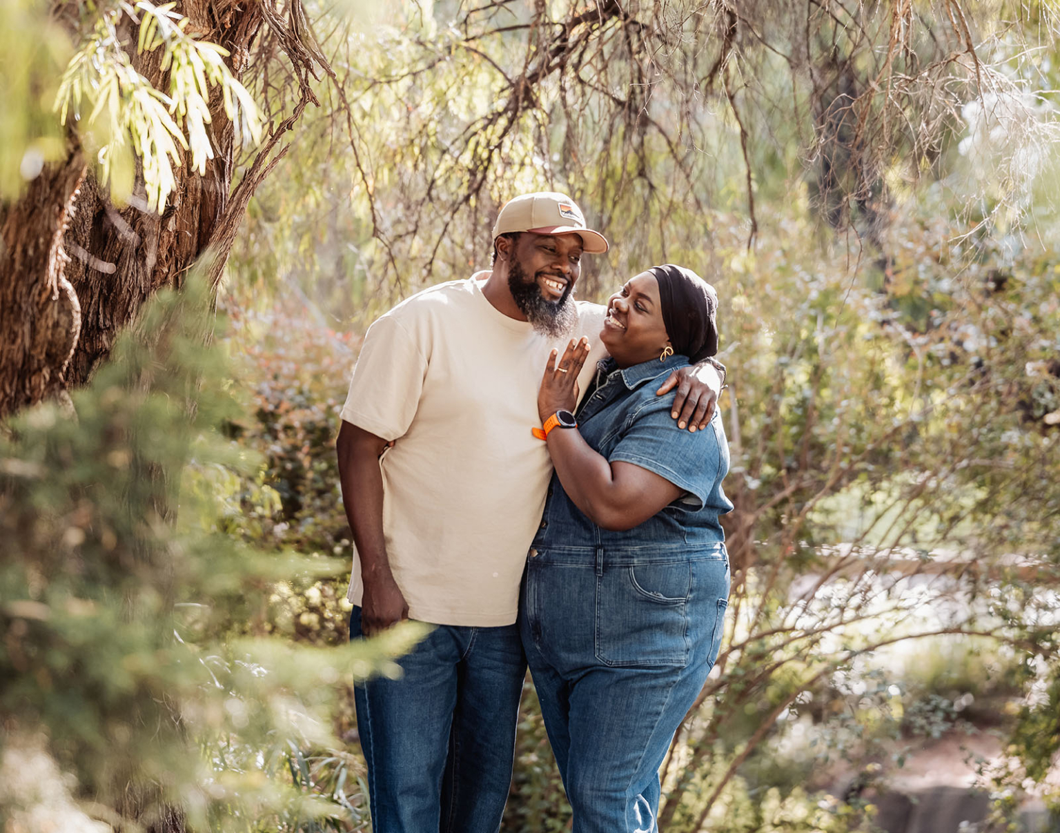 family photoshoot in veale gardens 7 Joyful couple embracing in lush nature, sunlight filtering through trees, expressing love and happiness.
