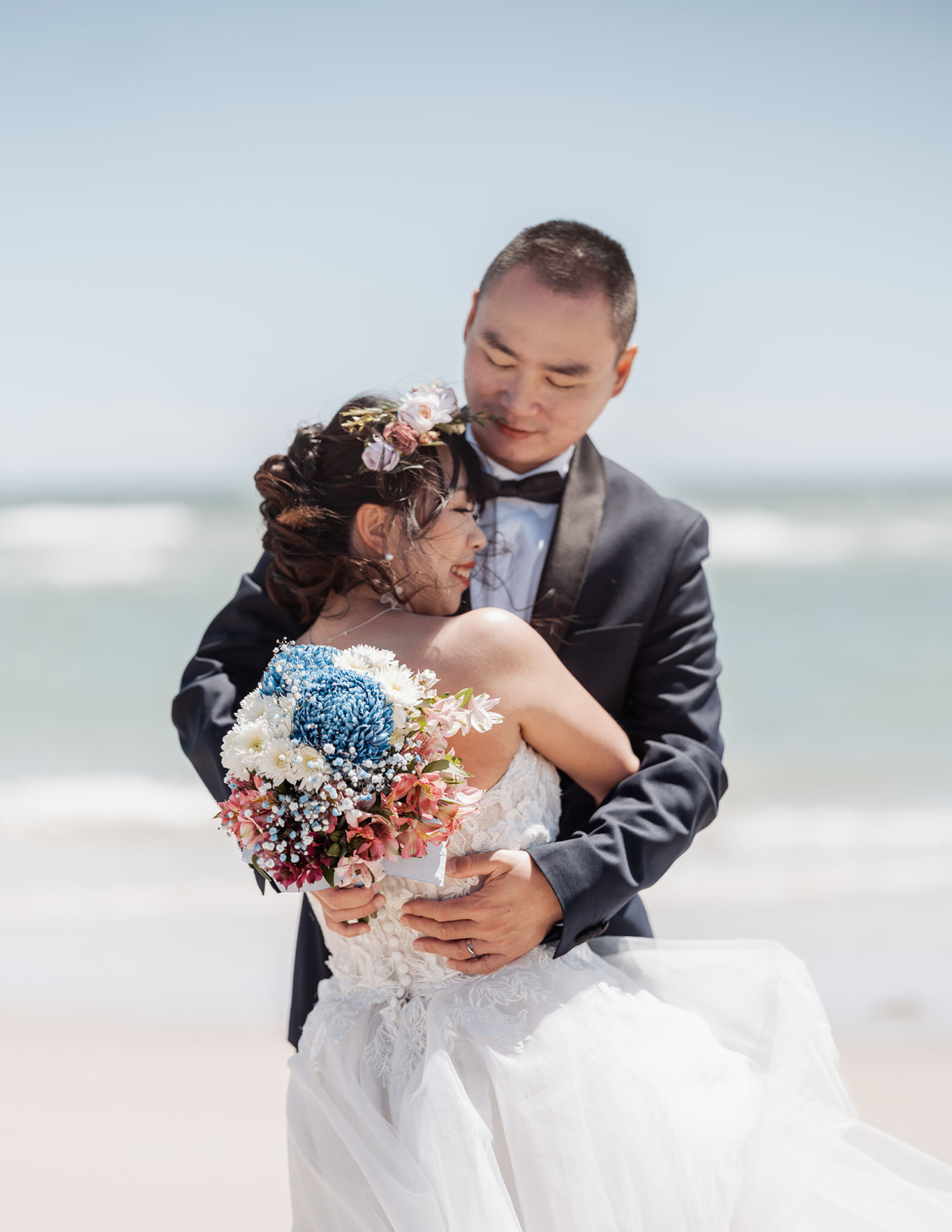 bumbunga lake photoshoot - tina & eric 39 Beach wedding couple embracing, bride in lace gown, serene ocean background.