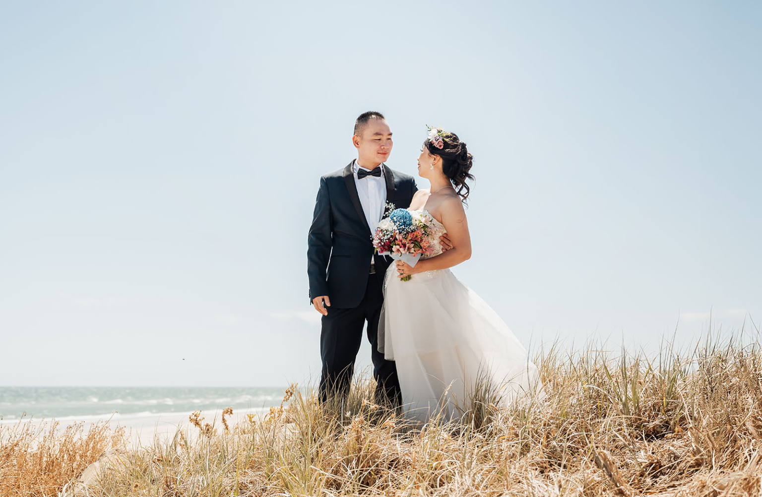 bumbunga lake photoshoot - tina & eric 35 Wedding couple on beach dune with ocean backdrop, floral details, and elegant attire.