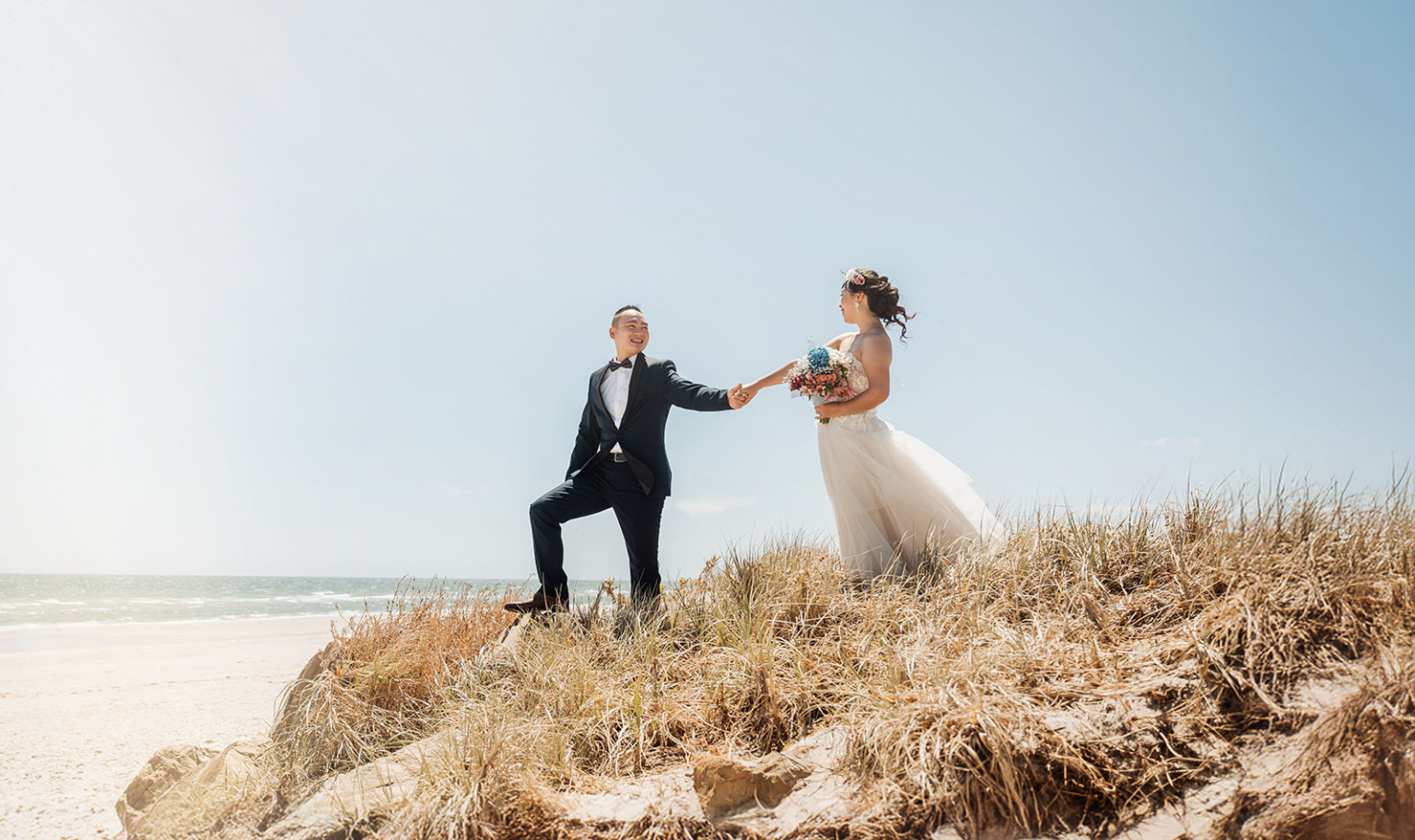 bumbunga lake photoshoot - tina & eric 34 Beach wedding couple on sandy dune with ocean backdrop and vibrant floral bouquet.