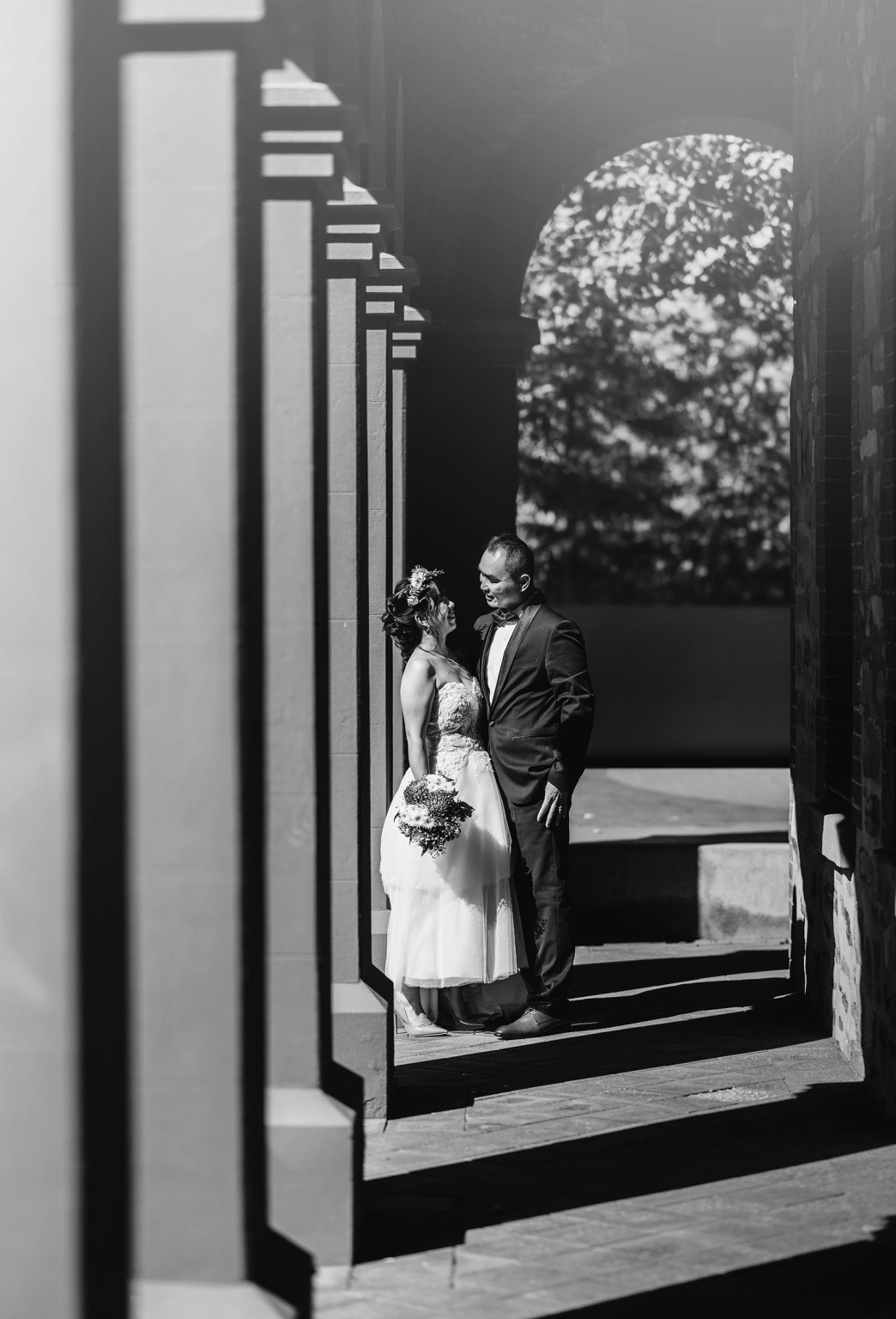 bumbunga lake photoshoot - tina & eric 60 Black and white wedding photo of affectionate couple in elegant attire under historical architectural arches.