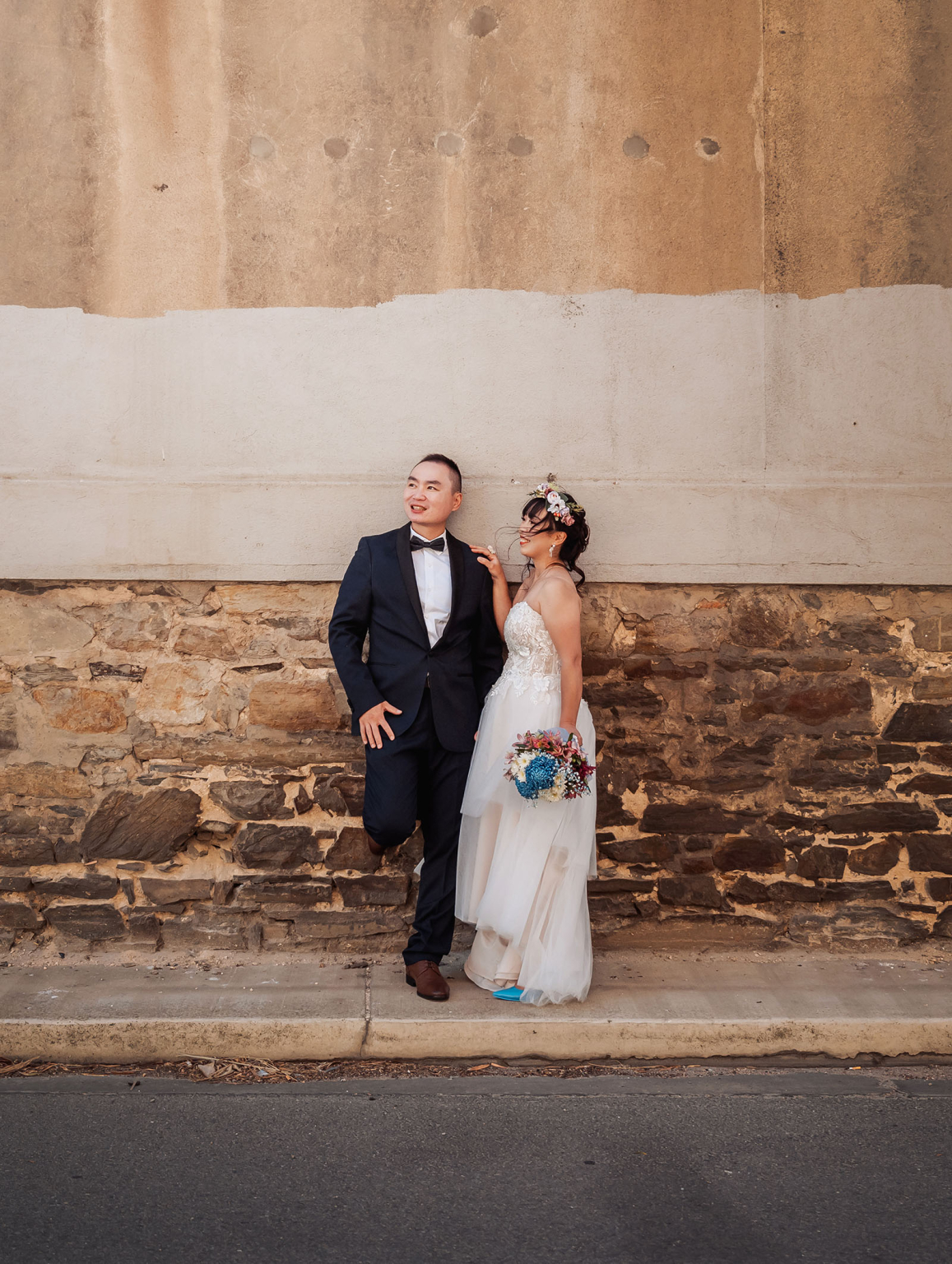 bumbunga lake photoshoot - tina & eric 50 Wedding couple against rustic stone wall with floral bouquet and elegant attire.
