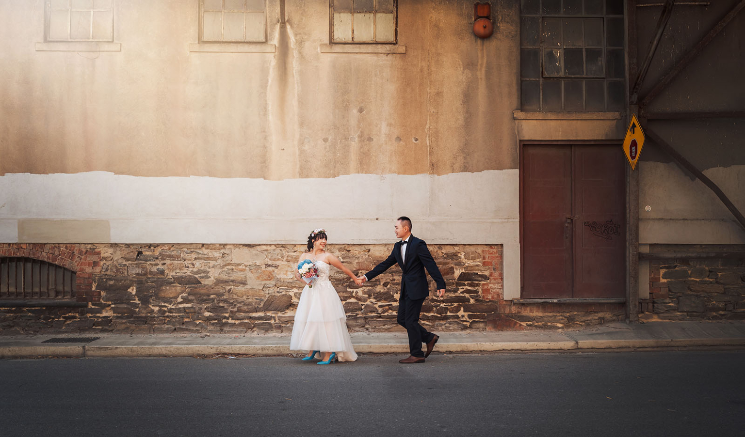 bumbunga lake photoshoot - tina & eric 48 Bride and groom wedding portrait in elegant attire, standing before a rustic urban wall.