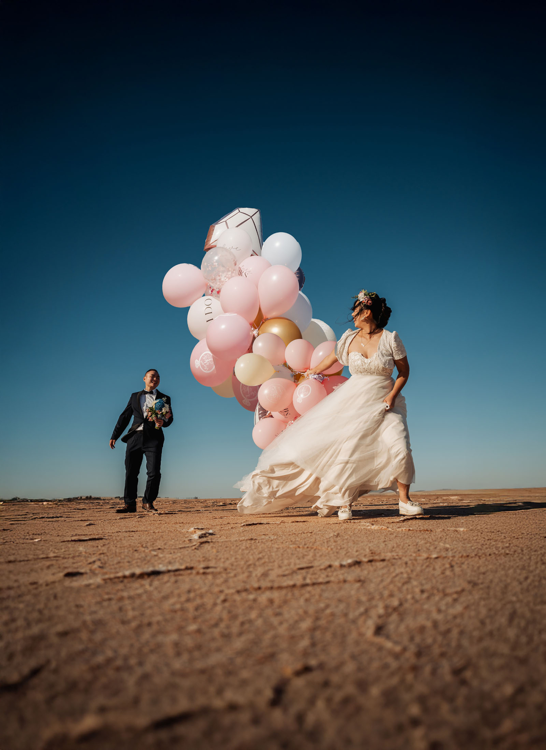 bumbunga lake photoshoot - tina & eric 66 Bride with balloons and groom in desert wedding setting, joyful and festive atmosphere.