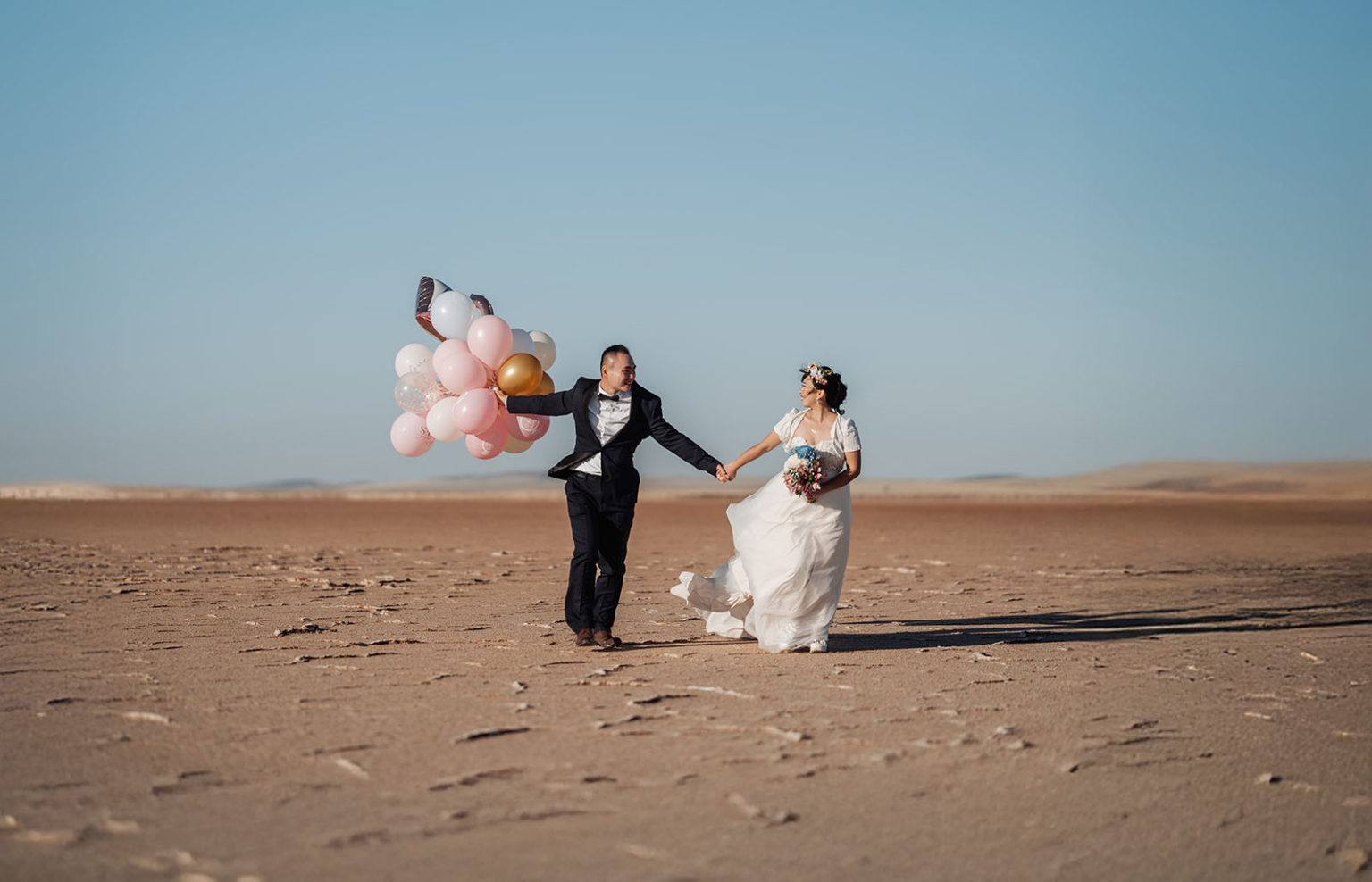 bumbunga lake photoshoot - tina & eric 68 Desert wedding couple with colorful balloons under clear blue sky.