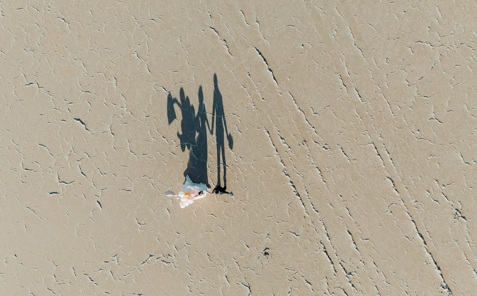 bumbunga lake photoshoot - tina & eric 73 Aerial view: dry lake bed, vibrant balloons, couples shadow, desert landscape.