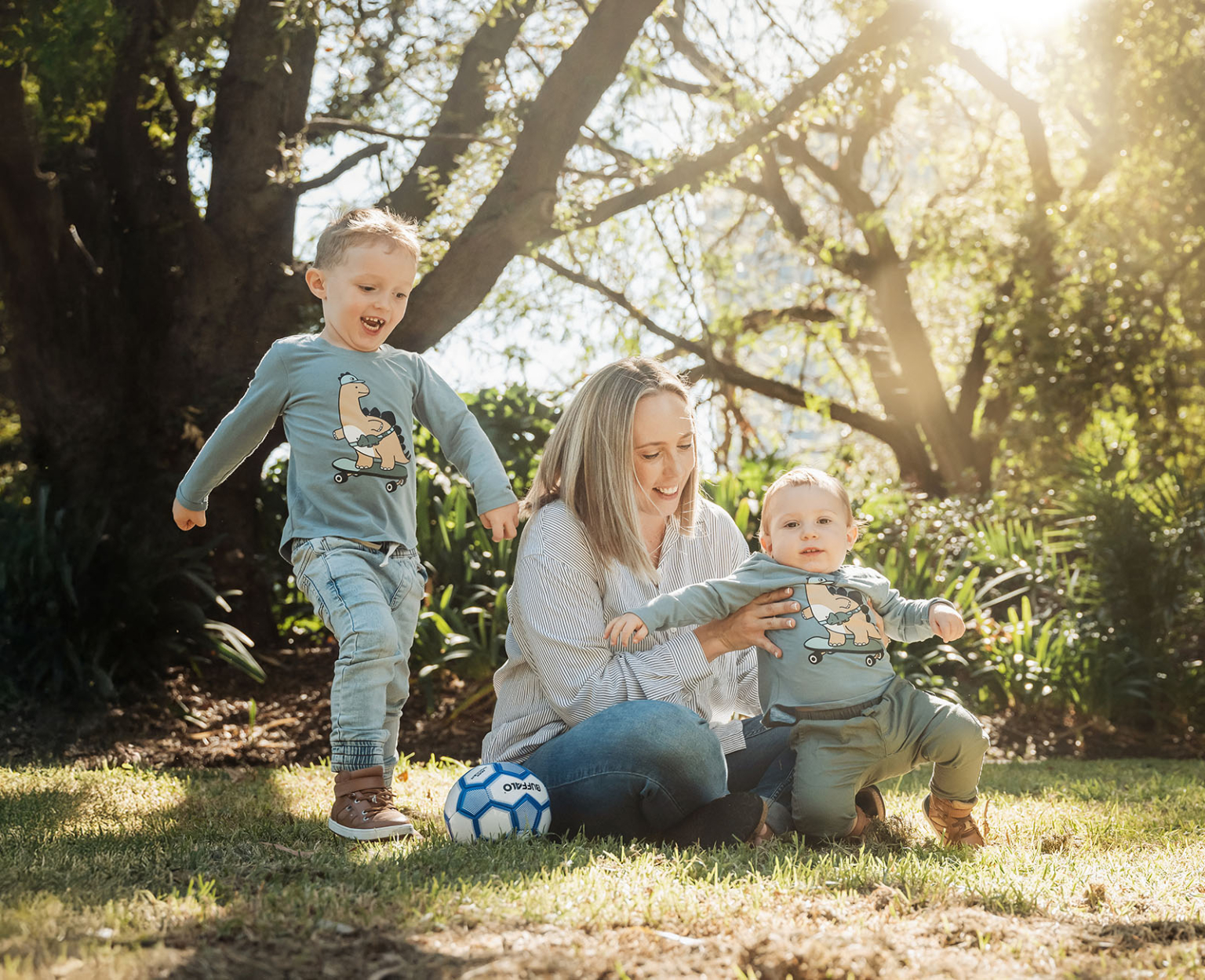 veale gardens family photography 118 Family joy: Woman, children playing outdoors, sunlit nature, bonding, green grass, cartoon clothes.
