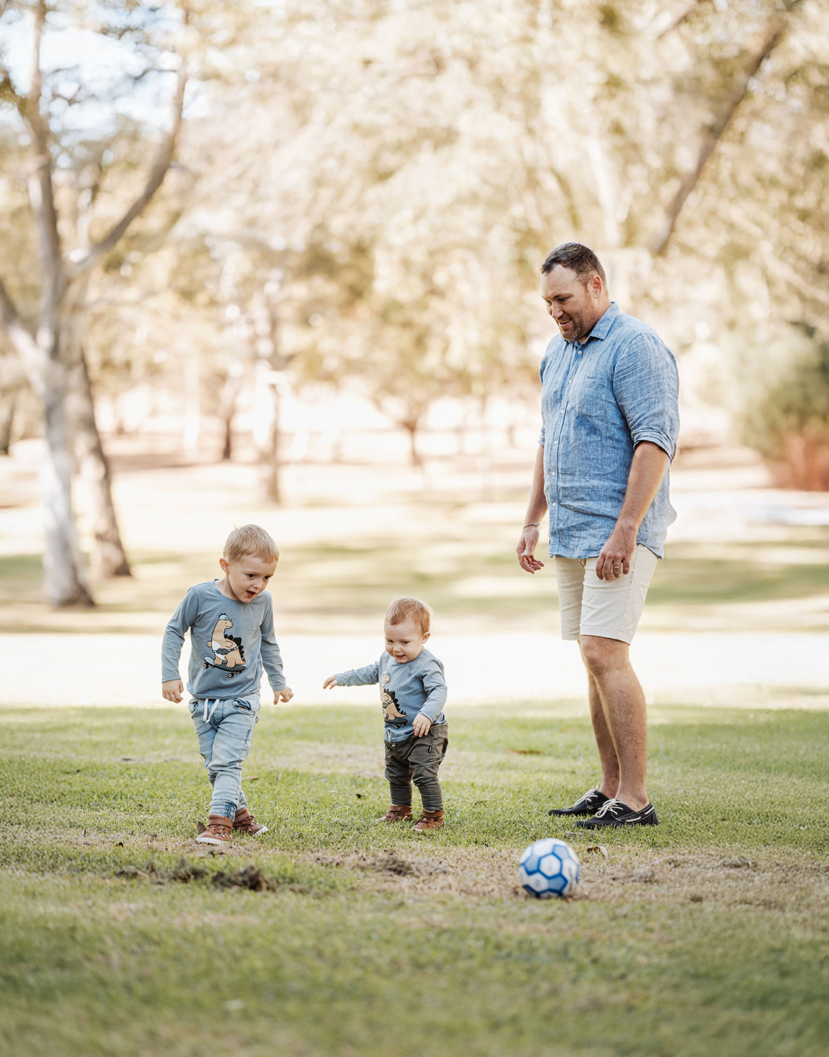 veale gardens family photography 114 A joyful family enjoys a sunny day playing soccer in a park.